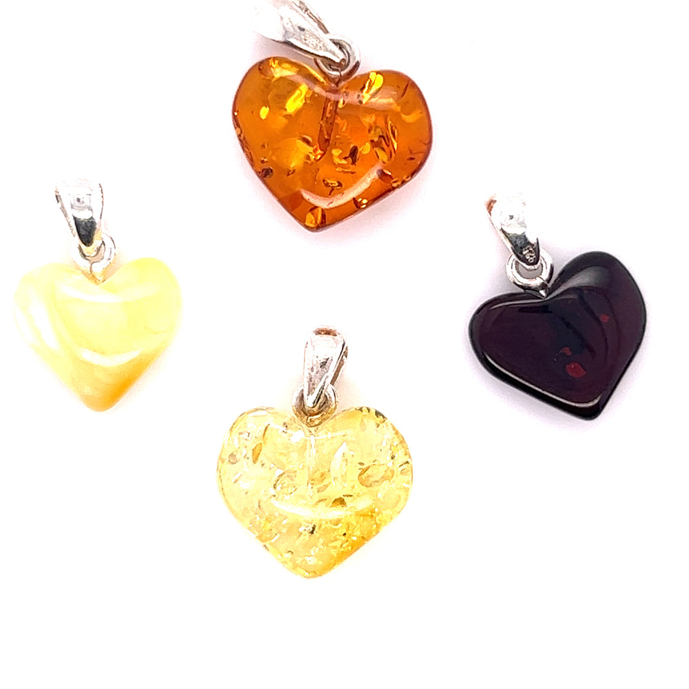Four Charming Baltic Amber Heart Pendants on a white background, made with .925 Sterling Silver from Super Silver.