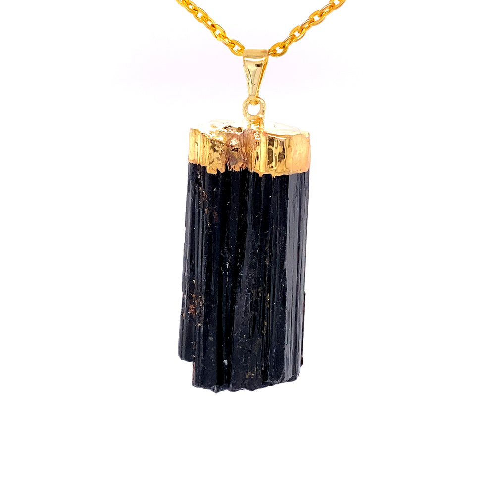 A Super Silver raw crystal pendant with gold cap featuring a raw black tourmaline on a gold chain.