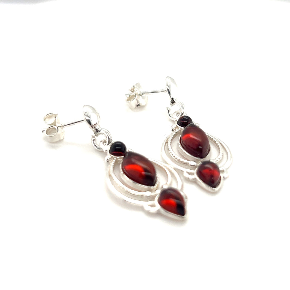
                  
                    A pair of Fancy Marquise Shaped Baltic Amber Earrings with garnet stones in a swirling lace setting for a vintage charm.
                  
                