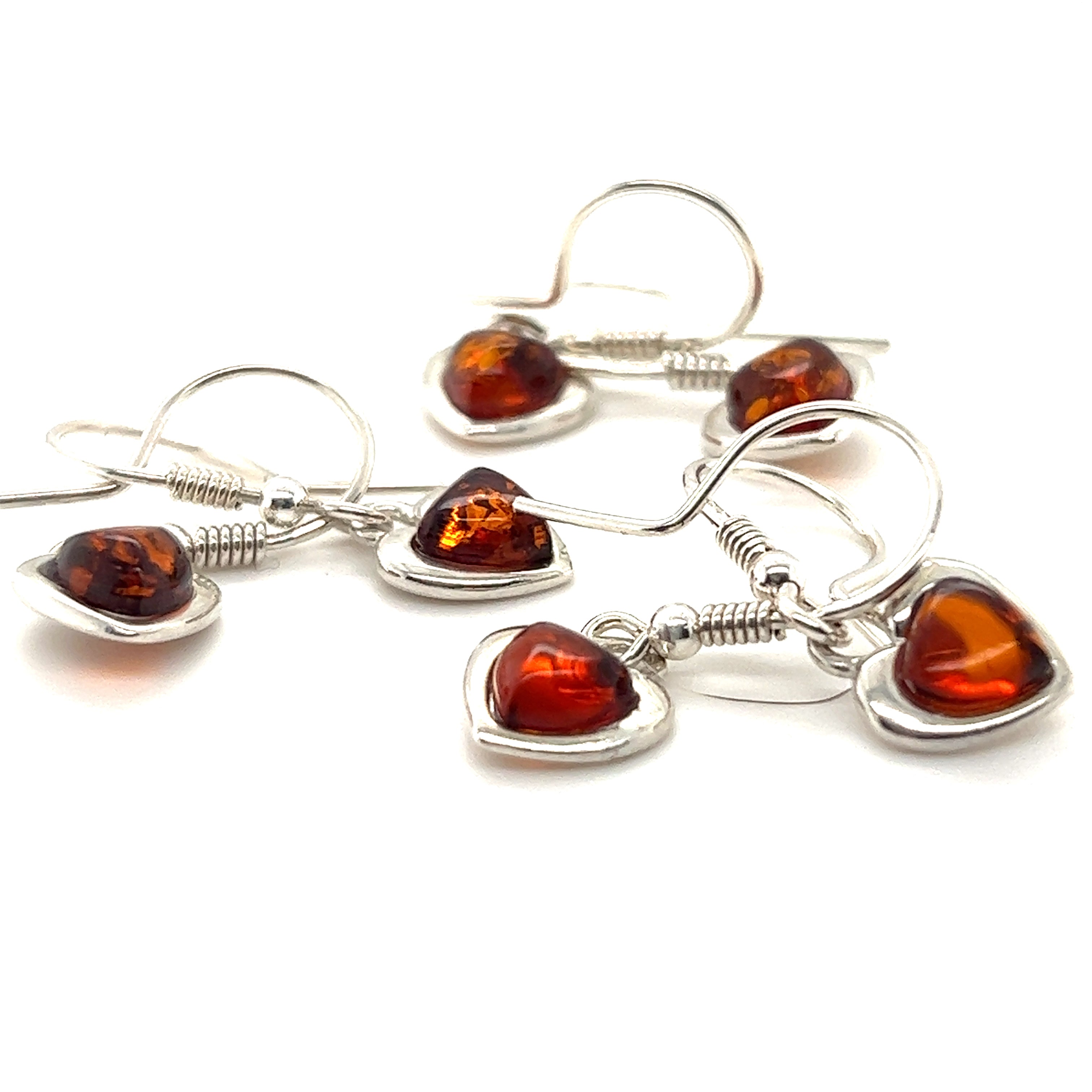 Three Dainty Amber Heart Earrings with soothing properties on a white background by Super Silver.
