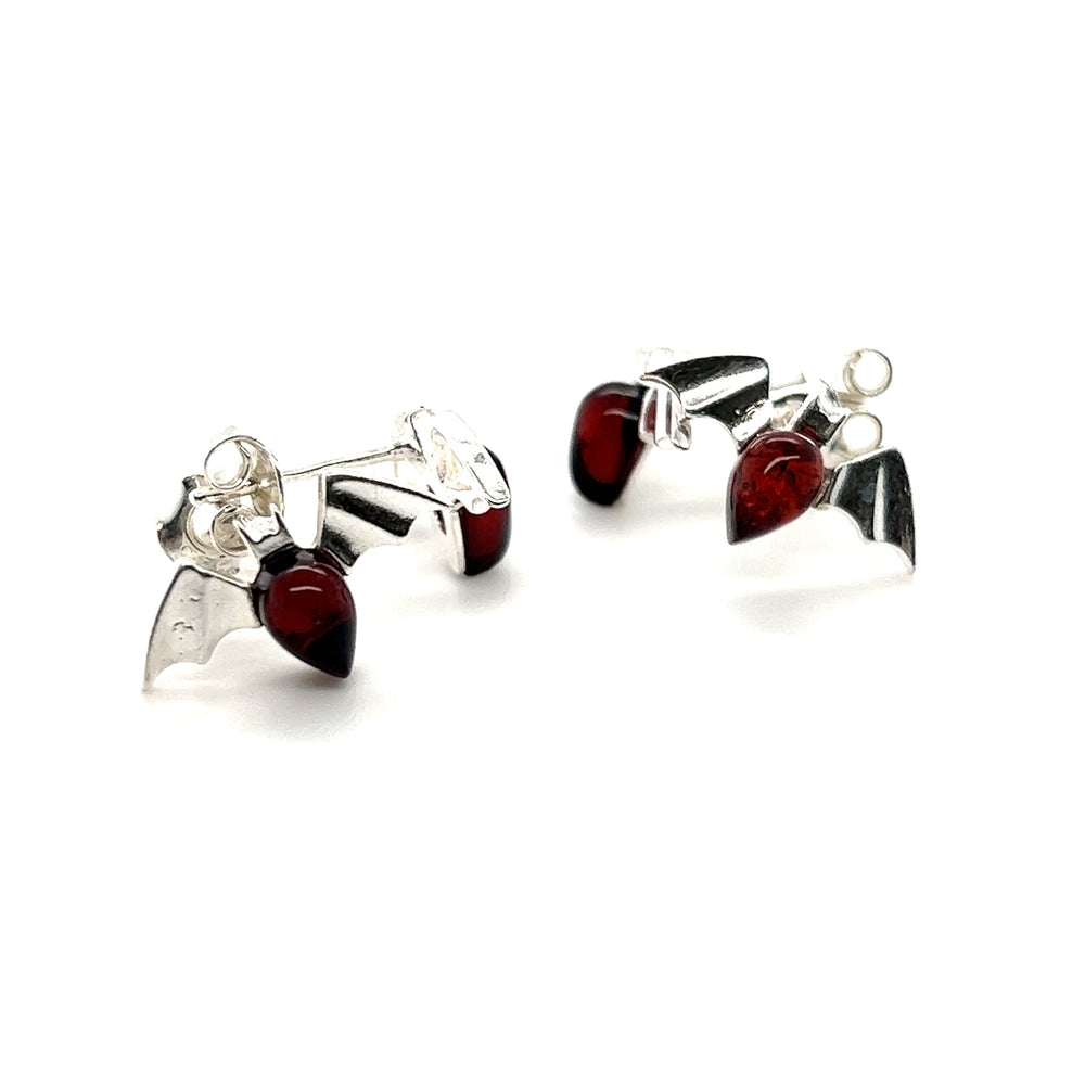 
                  
                    A pair of Enchanting Baltic Amber Bat Stud Earrings by Super Silver with cherry-colored glass.
                  
                
