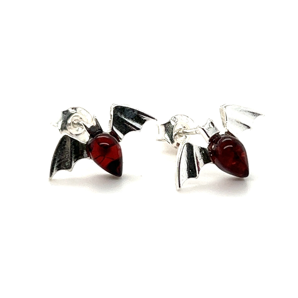 A pair of Enchanting Baltic Amber Bat Stud Earrings from the Super Silver brand with cherry-colored stones.