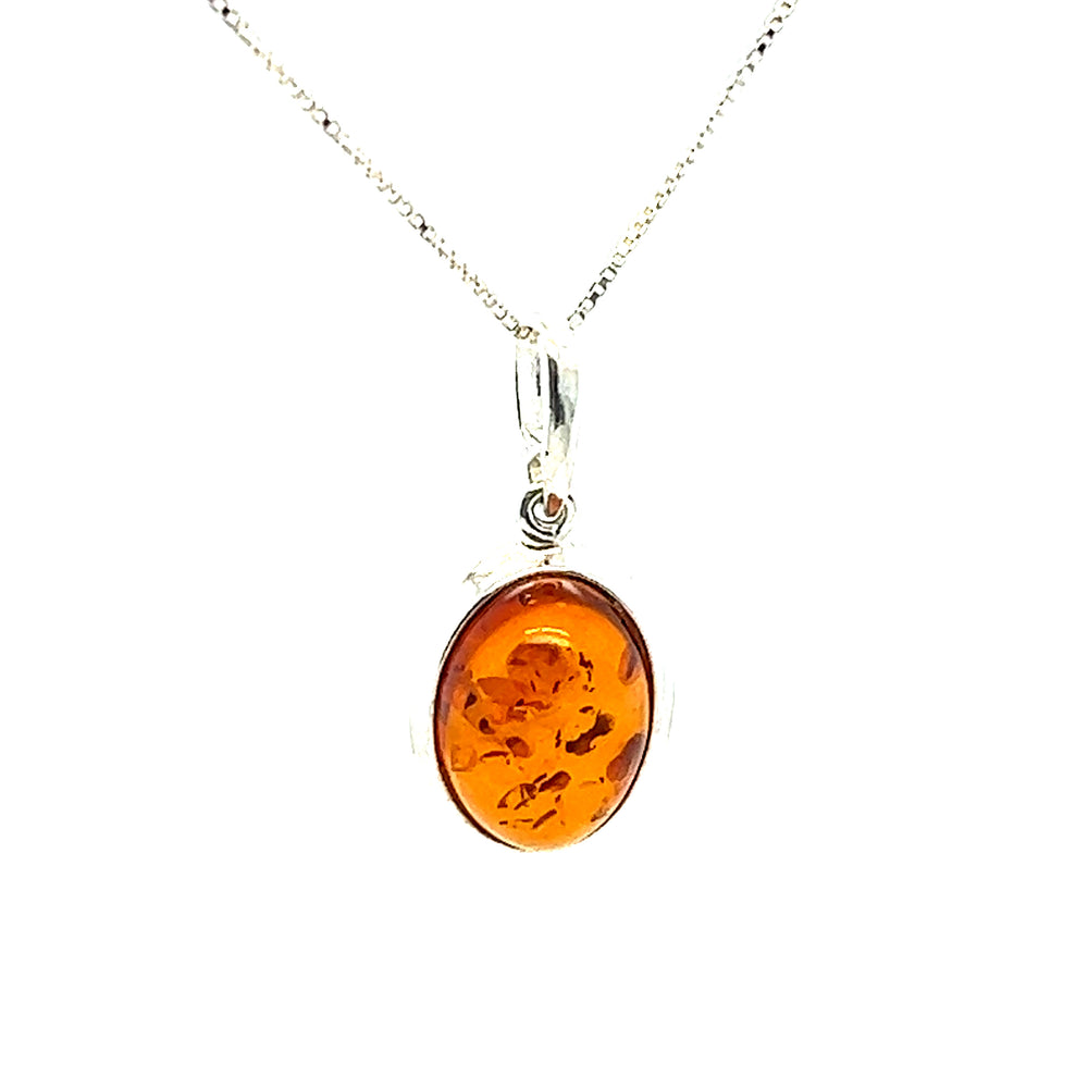A Simple Framed Oval Amber Pendant by Super Silver on a silver chain with a sterling silver bezel.