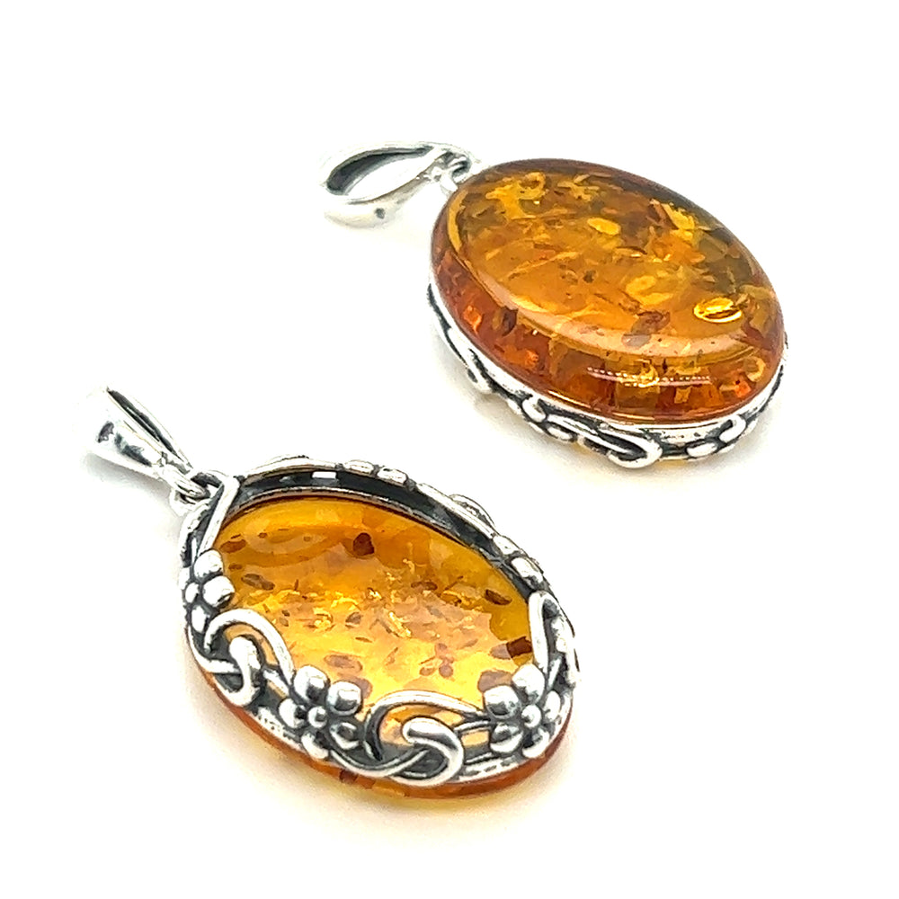 
                  
                    A pair of Super Silver Cognac Amber Oval Pendants with Floral Border on a white background showcasing vintage-styled pendant designs.
                  
                
