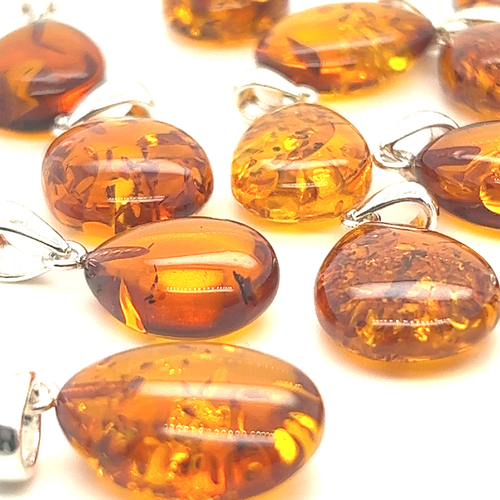 
                  
                    A collection of Super Silver Teardrop Amber Pendants exuding healing energy, beautifully displayed on a pristine white surface.
                  
                