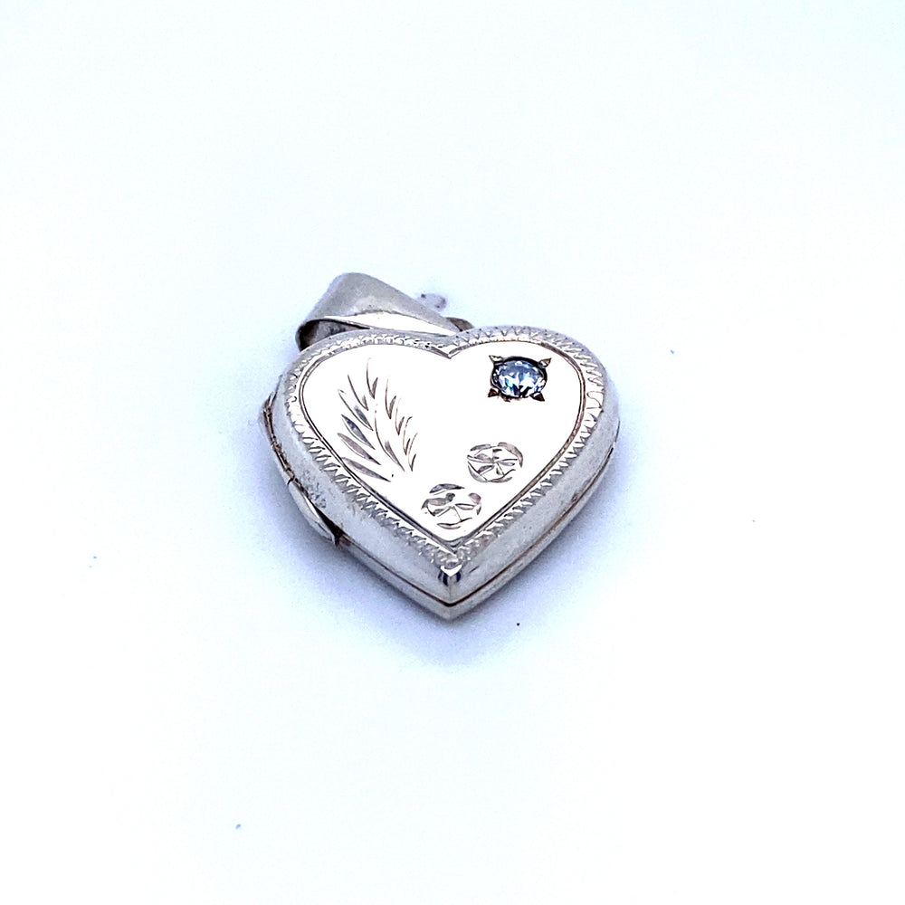 
                  
                    A Super Silver heart locket with a romantic charm, adorned with blue sapphires, and featuring a heart shaped locket with stone and lacy etching.
                  
                