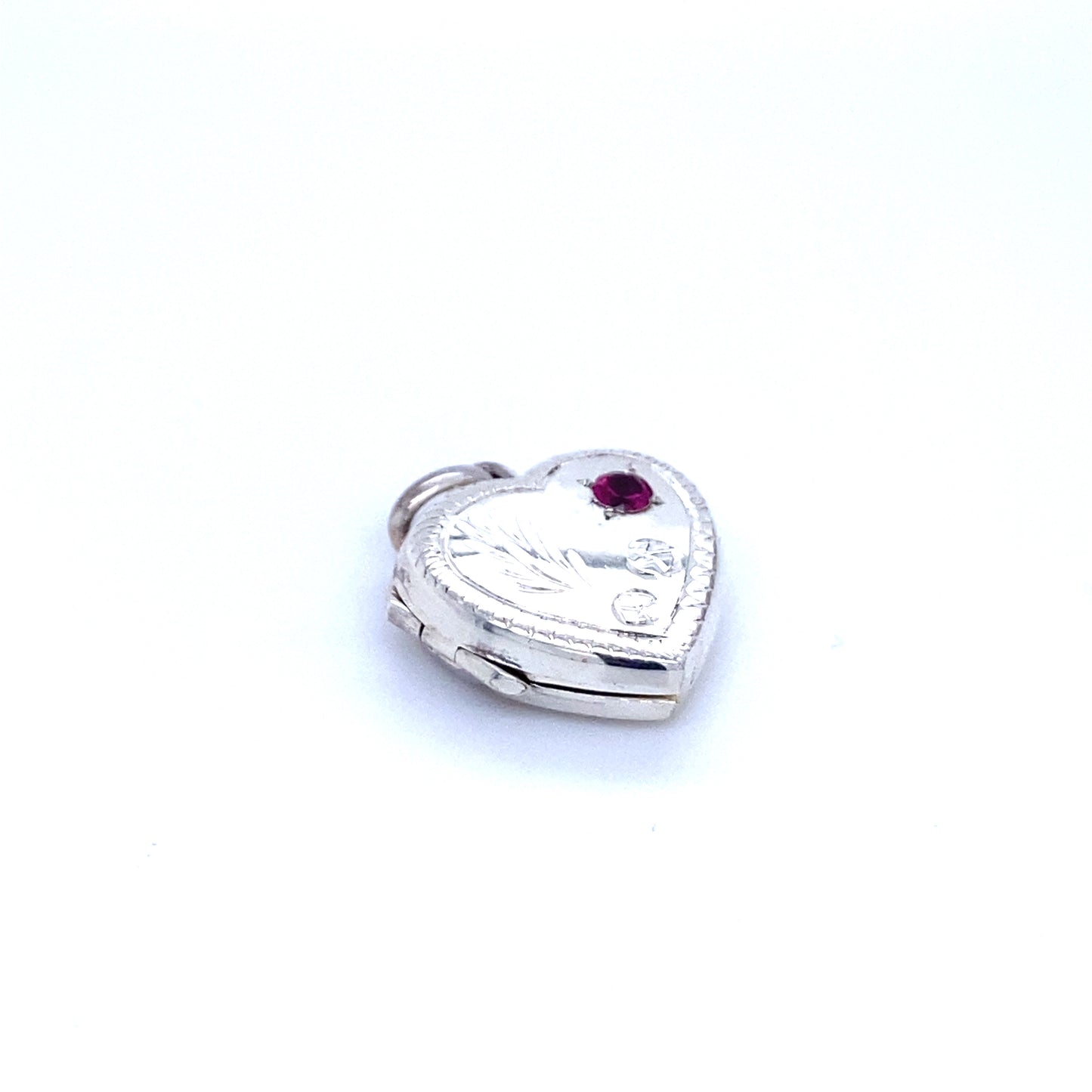 
                  
                    A Super Silver heart-shaped locket with a ruby stone and lacy etching, exuding romantic charm.
                  
                
