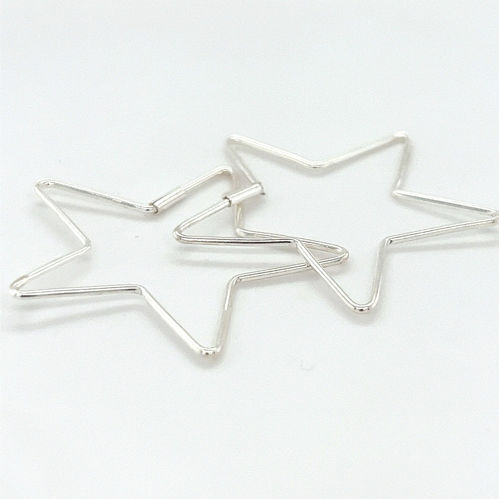 
                  
                    Two Delicate Star Shaped Hoops by Super Silver on a white surface.
                  
                