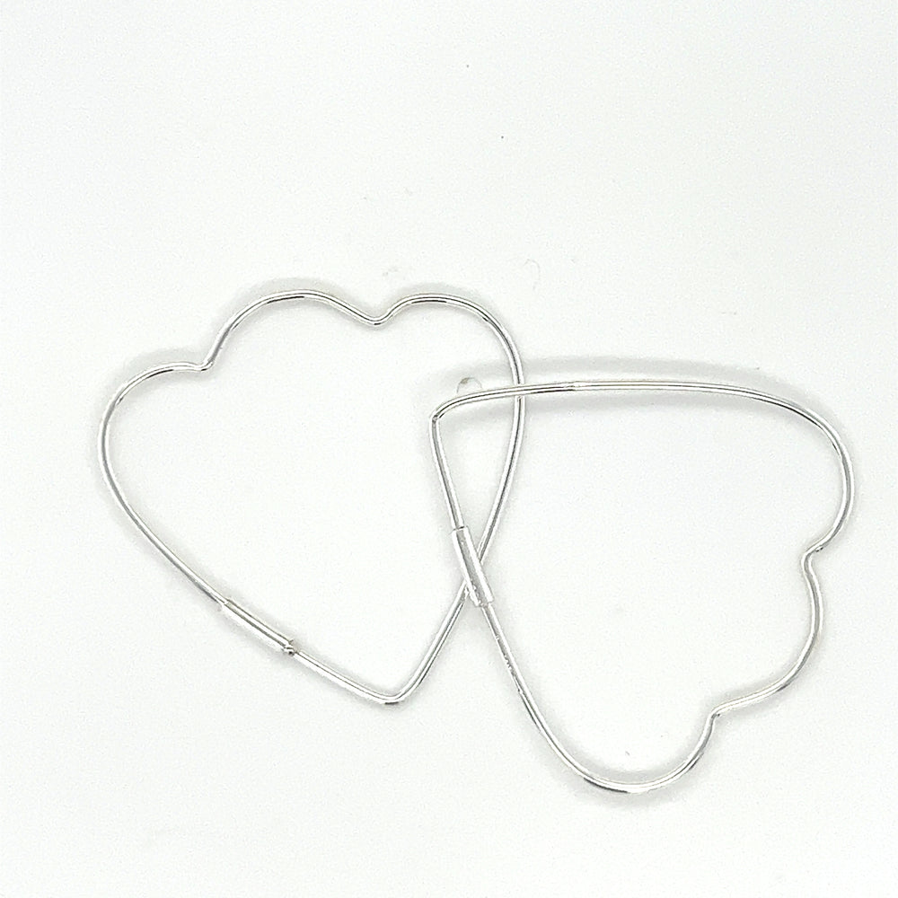 
                  
                    Two Delicate Heart Shaped Hoops by Super Silver on a white surface.
                  
                