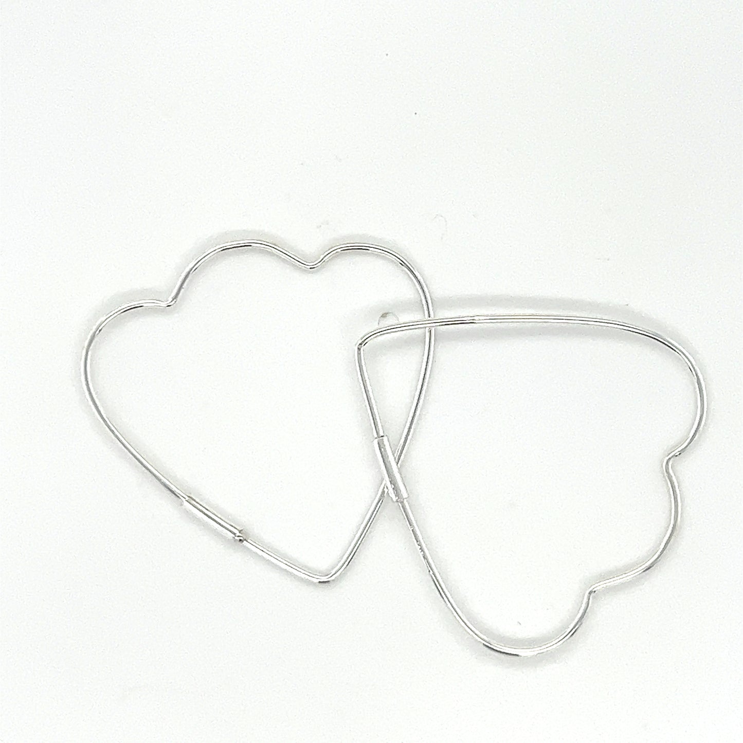 
                  
                    Two Delicate Heart Shaped Hoops by Super Silver on a white surface.
                  
                