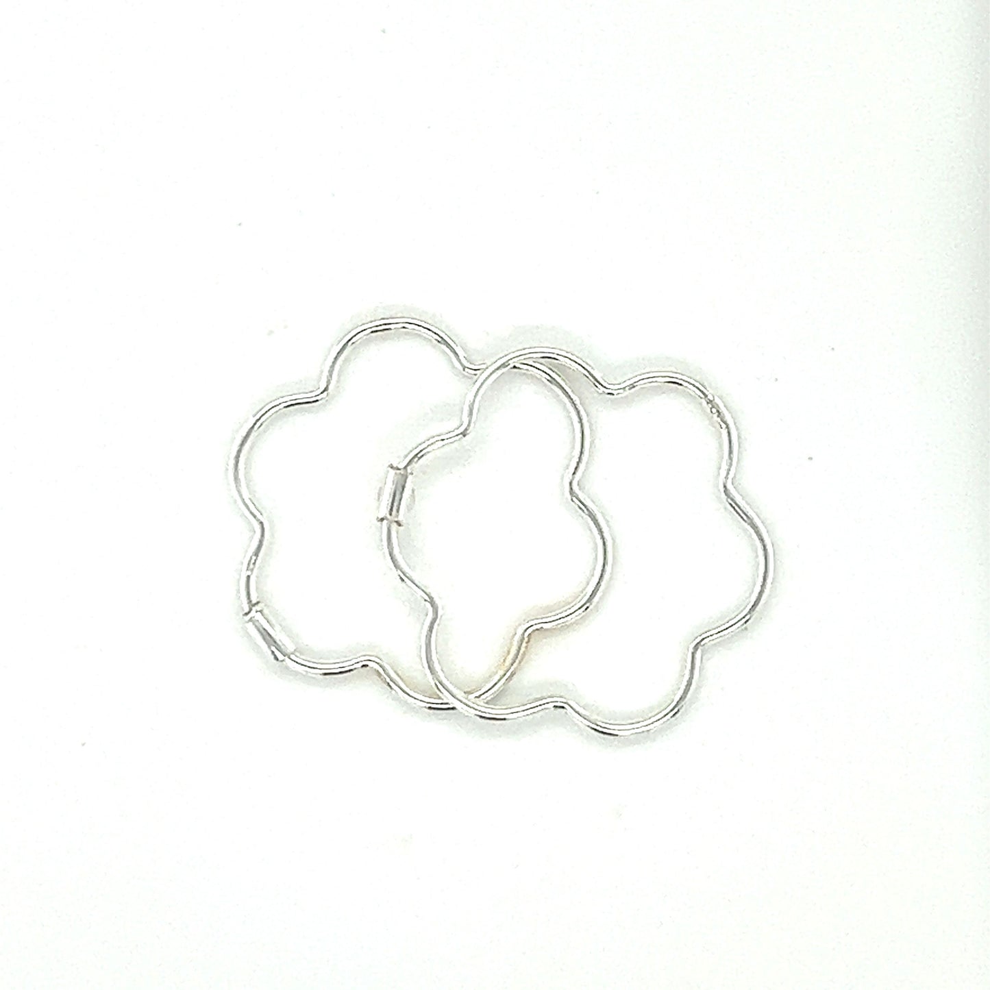 A minimalist Super Silver Delicate Flower Shaped Hoops displayed on a white surface.
