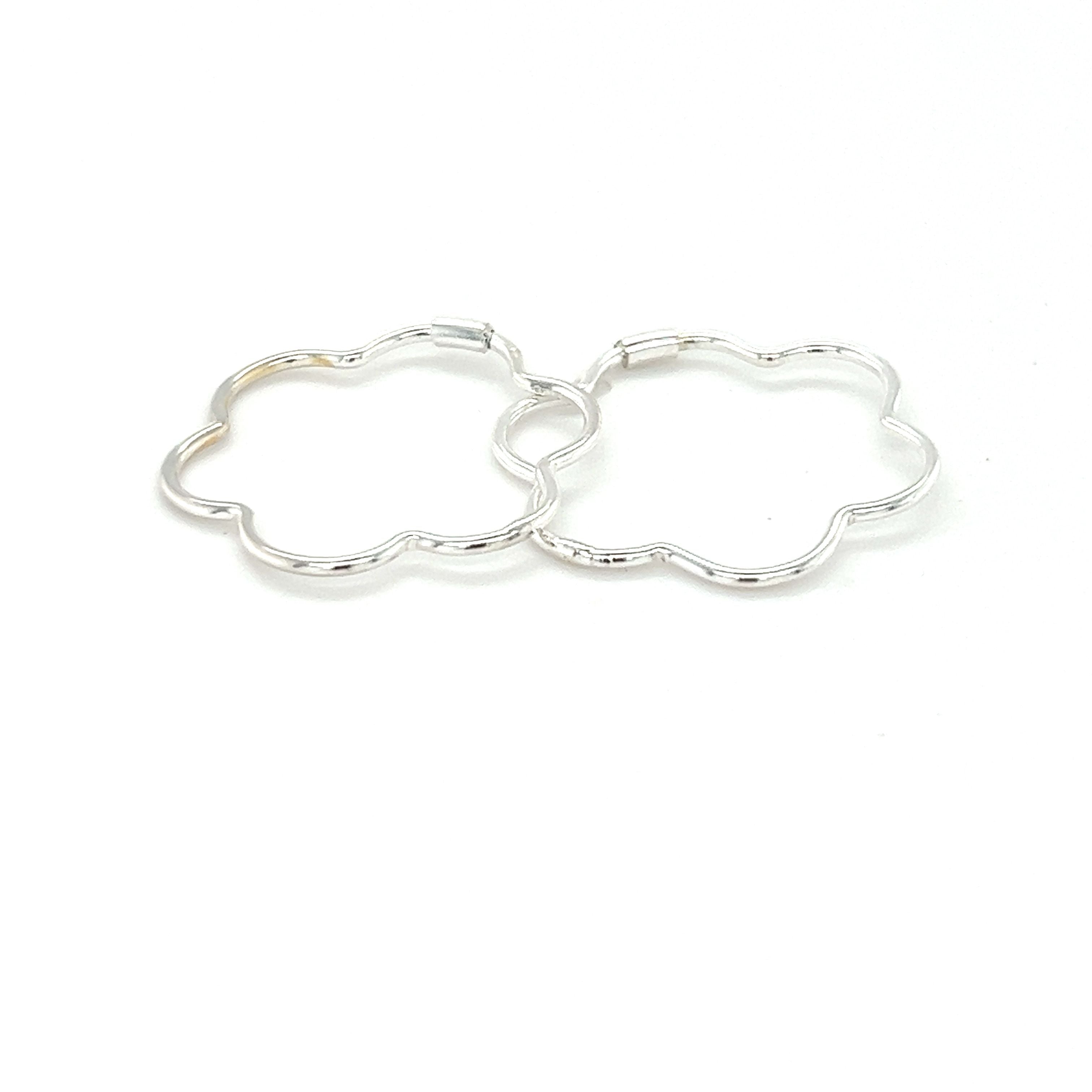 A minimalist pair of Super Silver delicate flower shaped hoops on a white background.