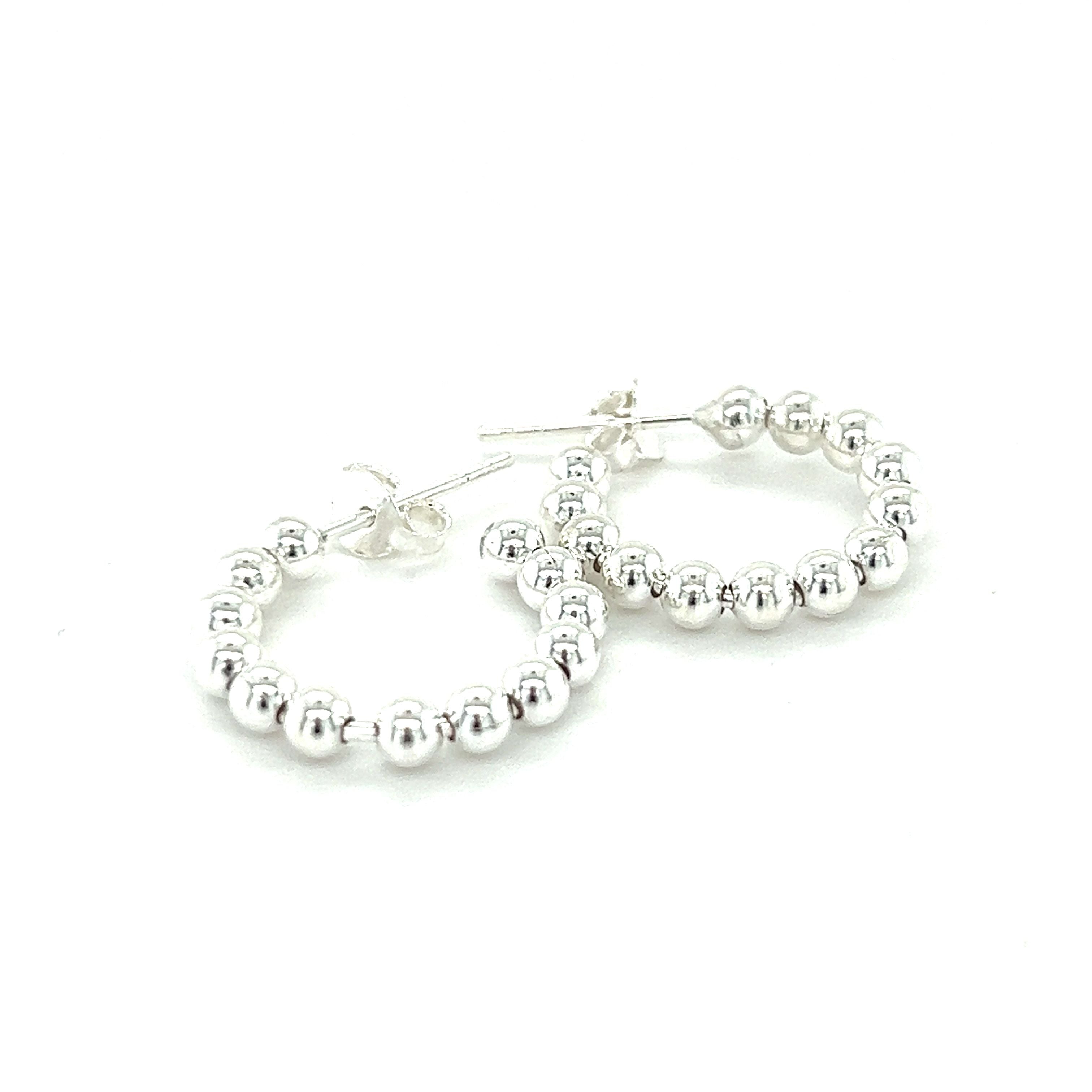 A minimalist pair of Super Silver Delicate Ball Hoops With Post earrings on a white background.