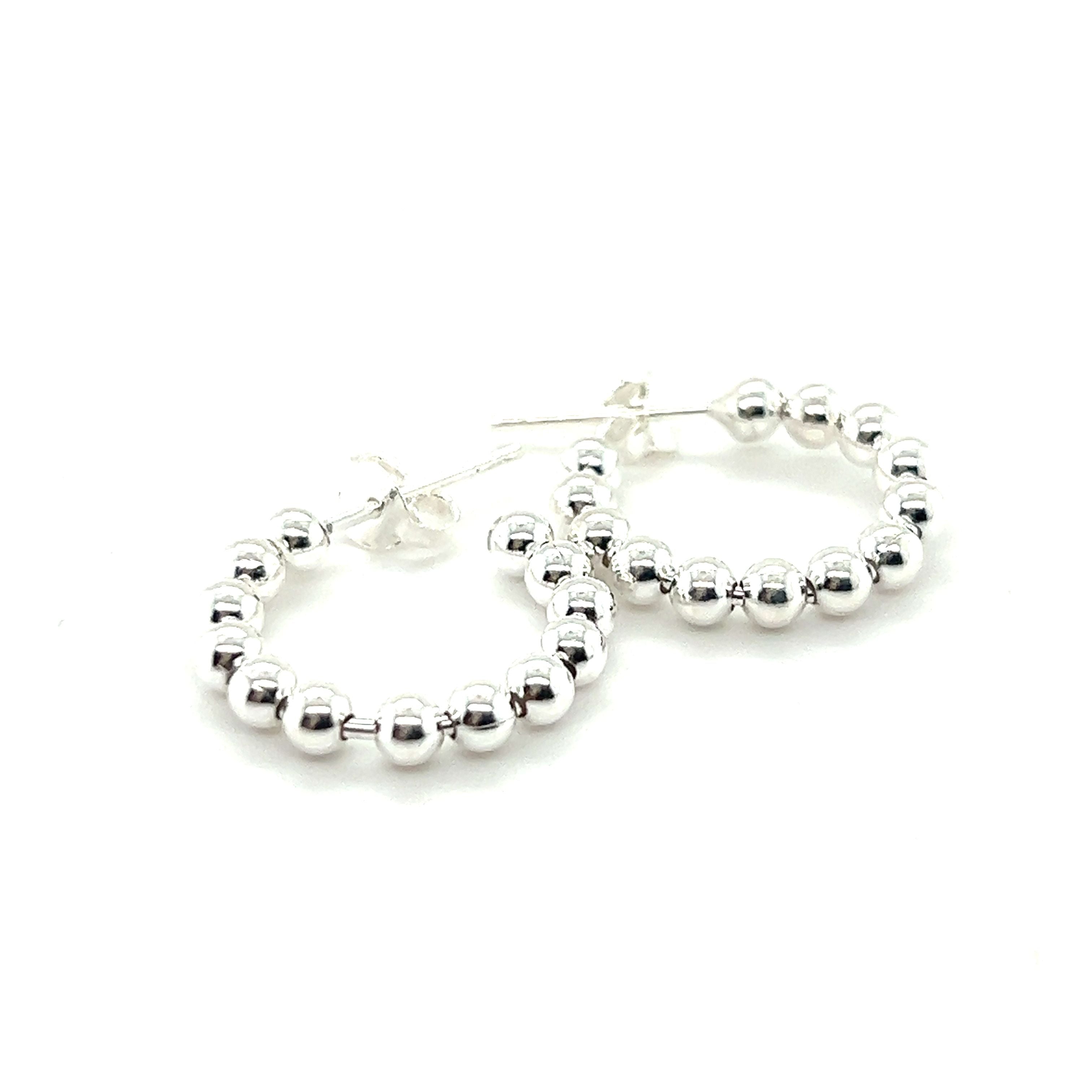 A pair of Super Silver Delicate Ball Hoops With Post earrings on a white background.