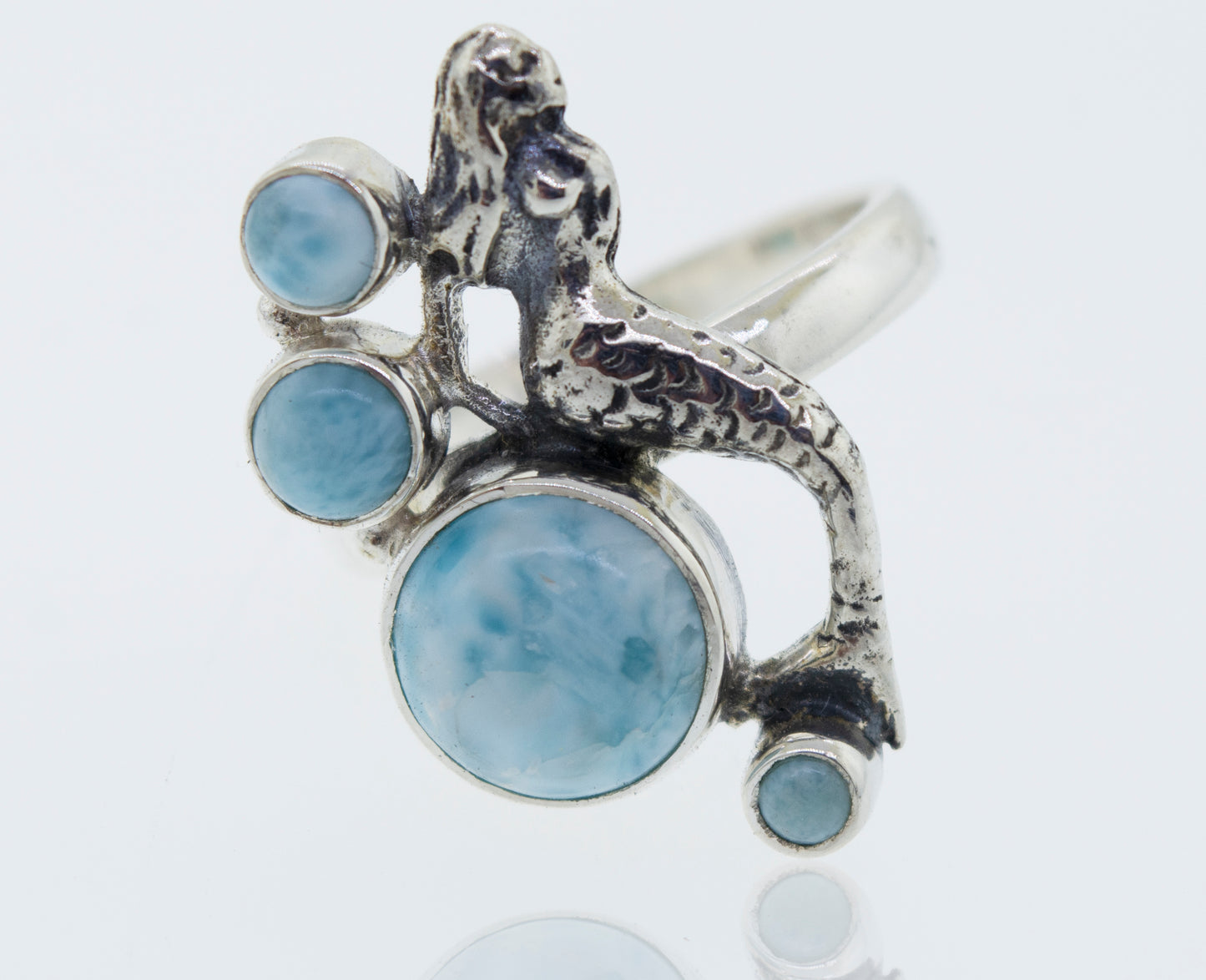 
                  
                    A sterling silver mermaid ring with Larimar adorned with vibrant blue stones reminiscent of the ocean.
                  
                