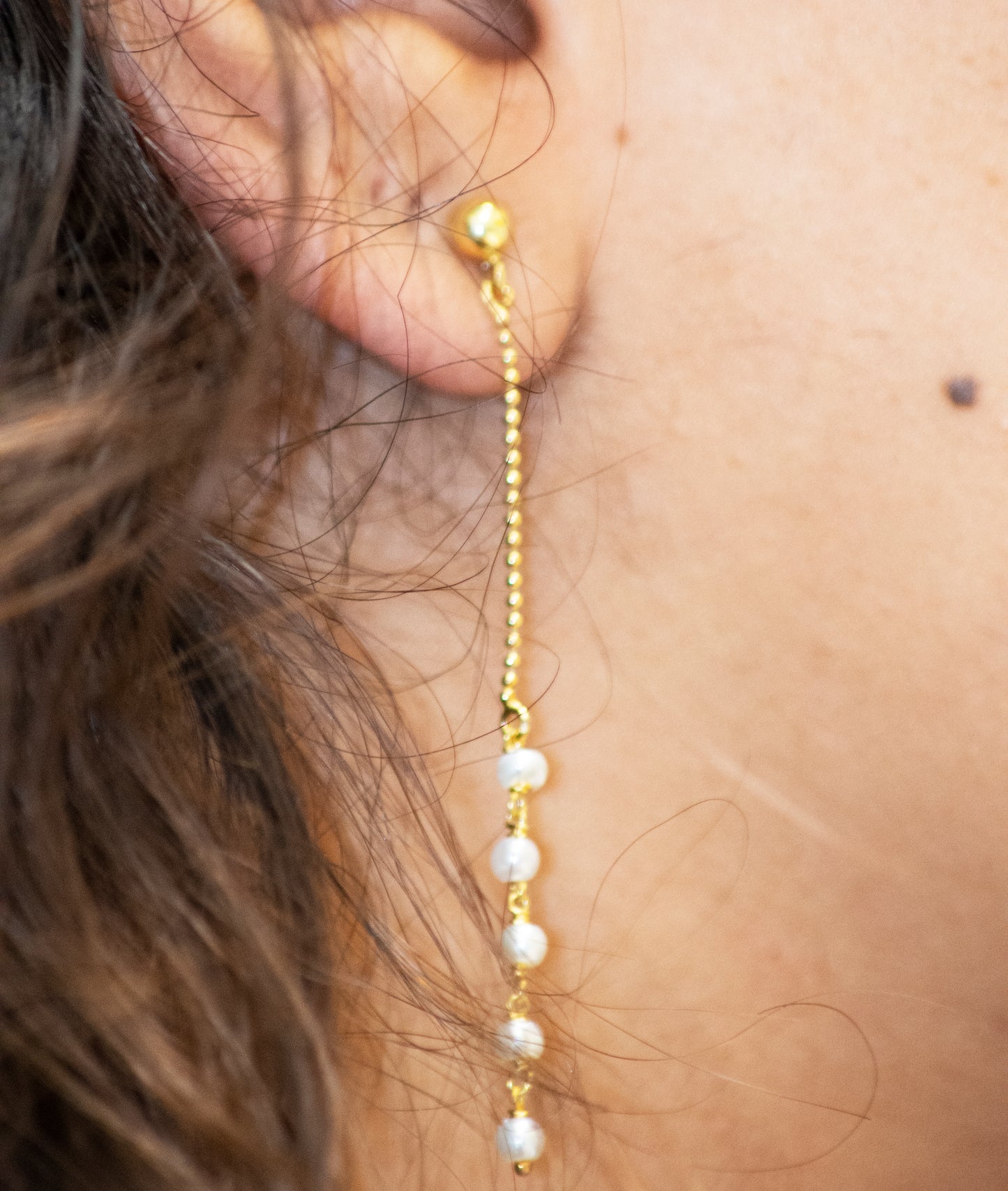 
                  
                    A close up of a woman's ear with a Super Silver 22 Karat Gold chain and Gold Plated Pearl Earrings.
                  
                