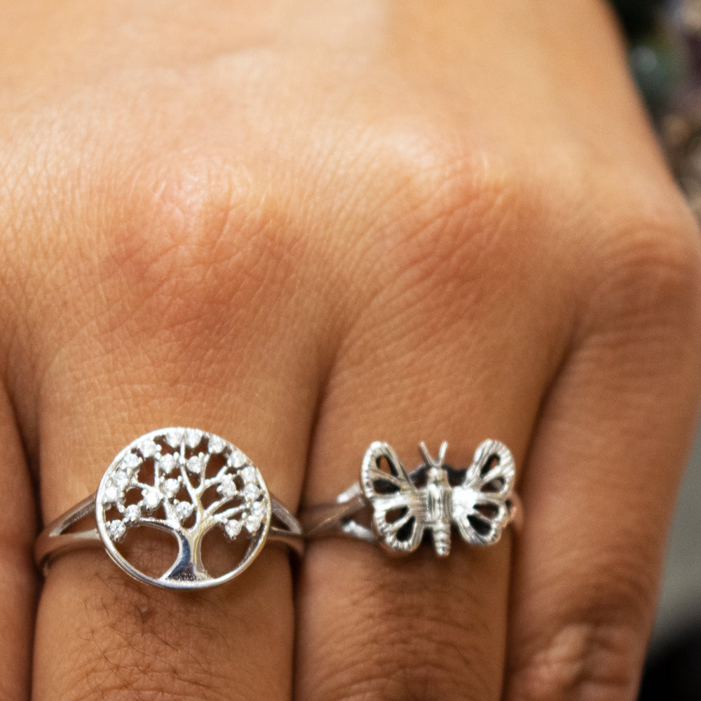 
                  
                    A woman's hand with a round, Tree Of Life Ring Cubic Zirconia Stones and a sterling silver butterfly ring.
                  
                