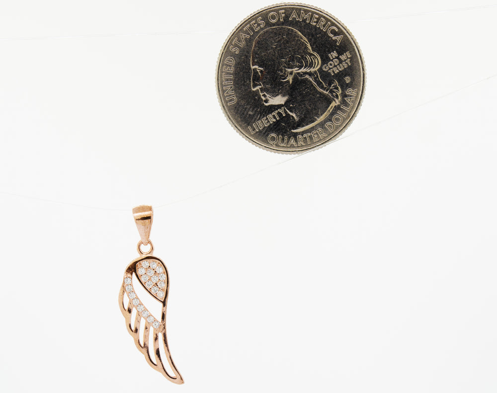 A Super Silver cubic zirconia feather-shaped pendant adorned with a feather, next to a penny.