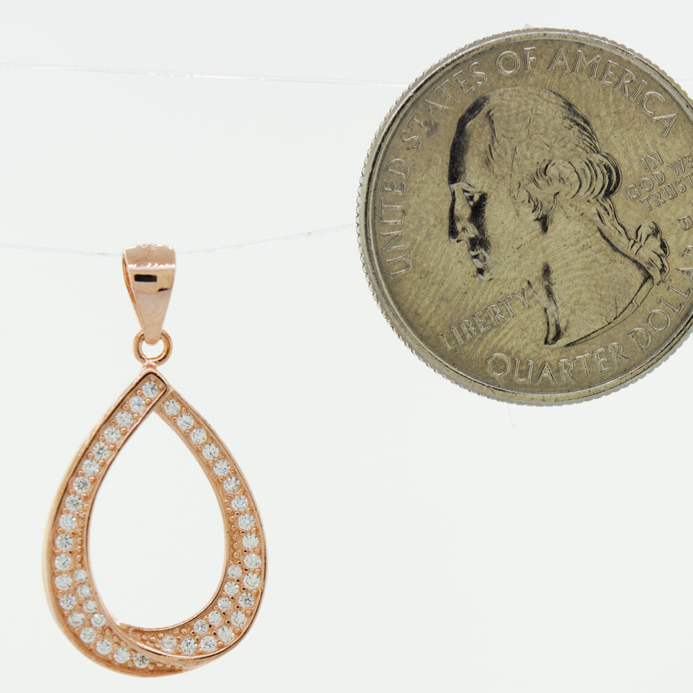 
                  
                    A Teardrop Shape Cubic Zirconia Pendant with a rose gold coin next to it.
                  
                