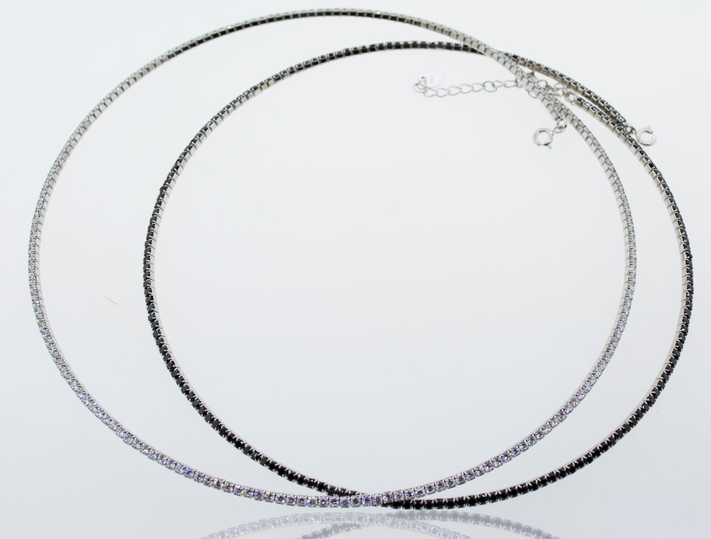 
                  
                    A pair of Super Silver cubic zirconia tennis necklaces with cubic zirconia stones on a white surface.
                  
                