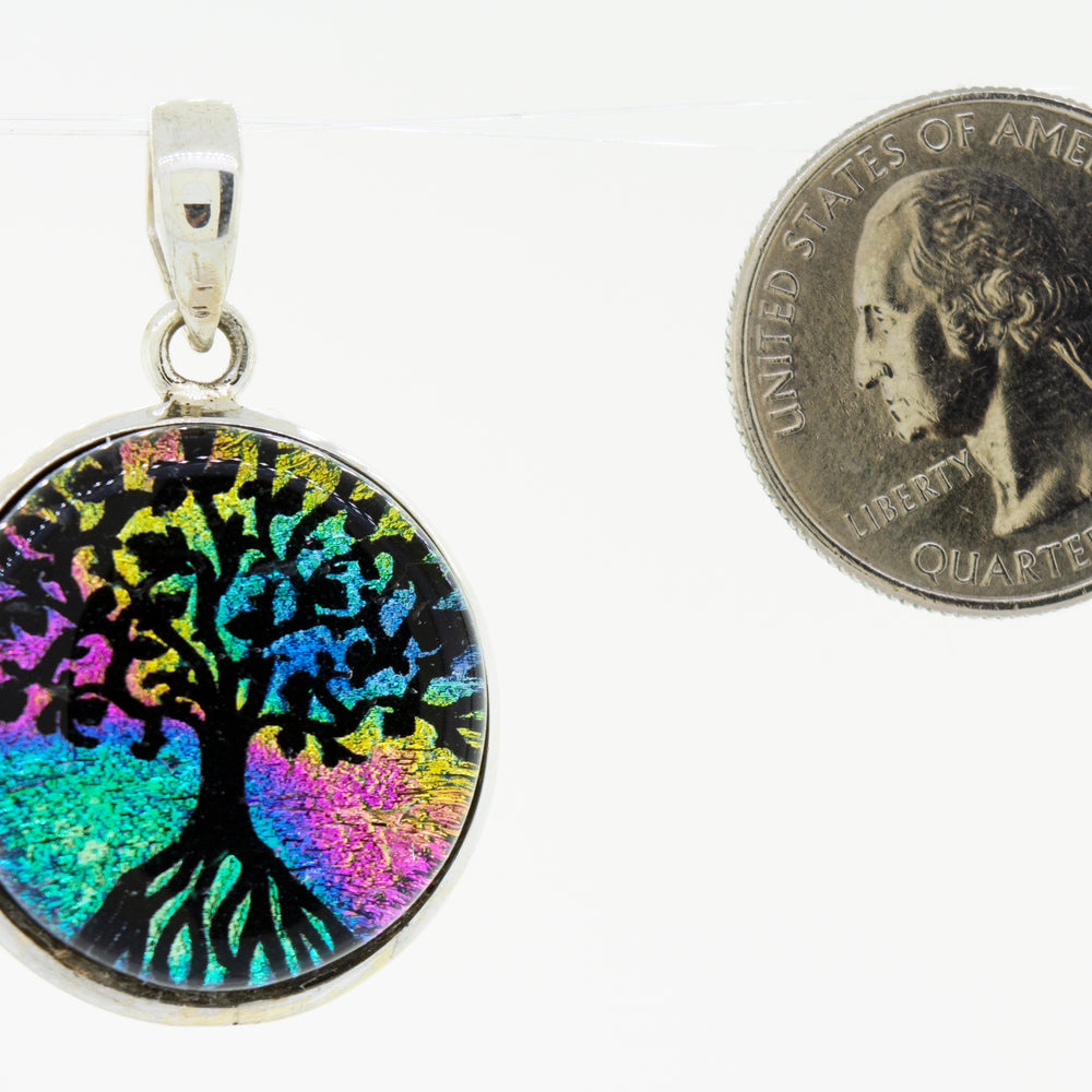 
                  
                    A vibrant Super Silver Dichroic Glass Tree of Life pendant, elegantly showcased next to a dime.
                  
                