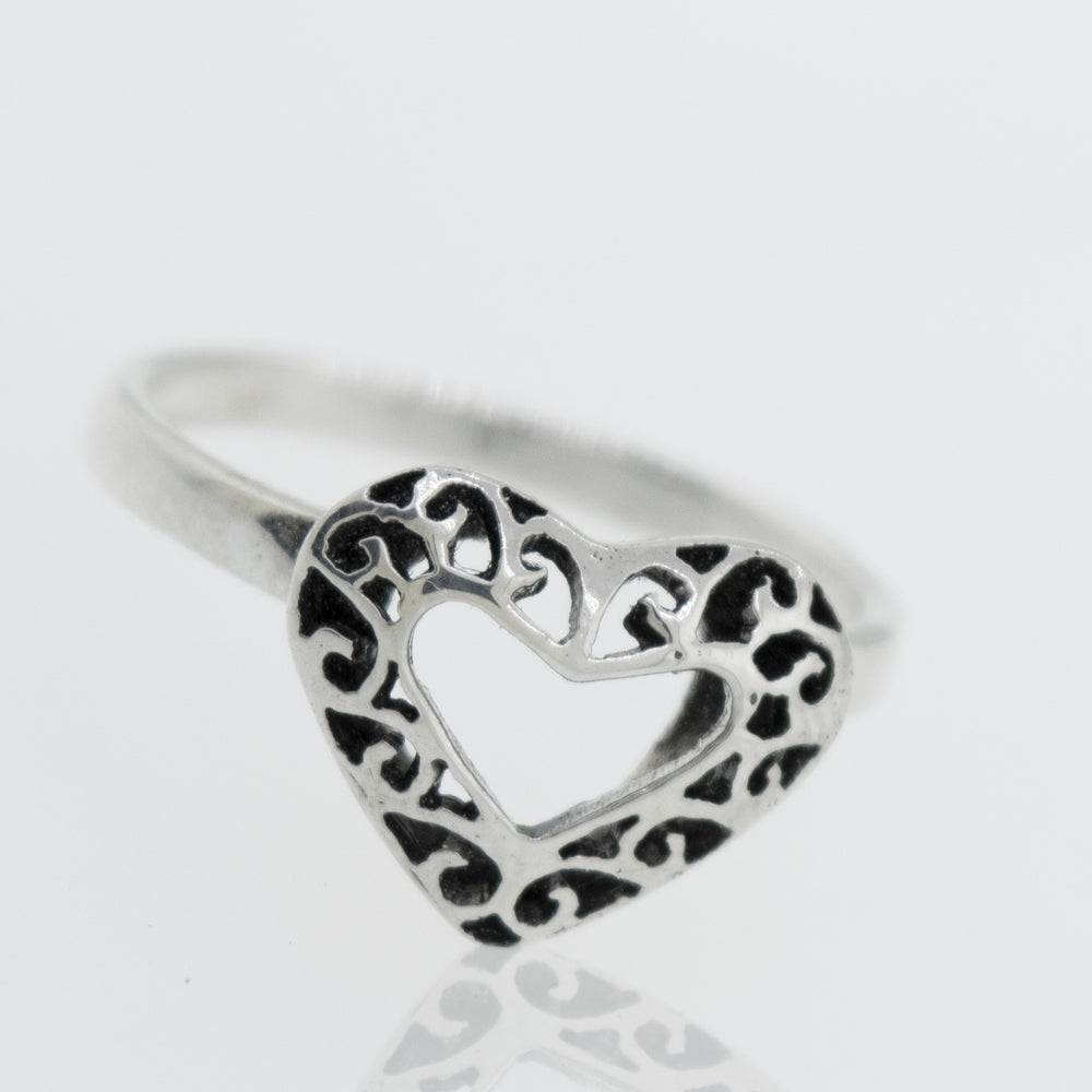 
                  
                    A minimalist Heart Shaped Ring with Filigree Detailing in the shape of a heart resting on a white surface, representing pure love.
                  
                