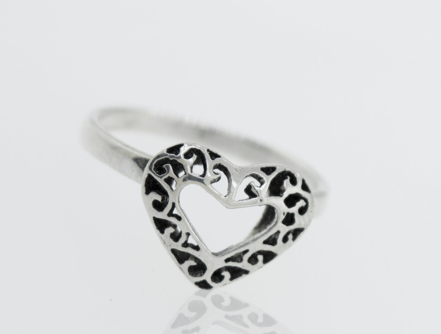
                  
                    A minimalist Heart Shaped Ring with Filigree Detailing in the shape of a heart resting on a white surface, representing pure love.
                  
                