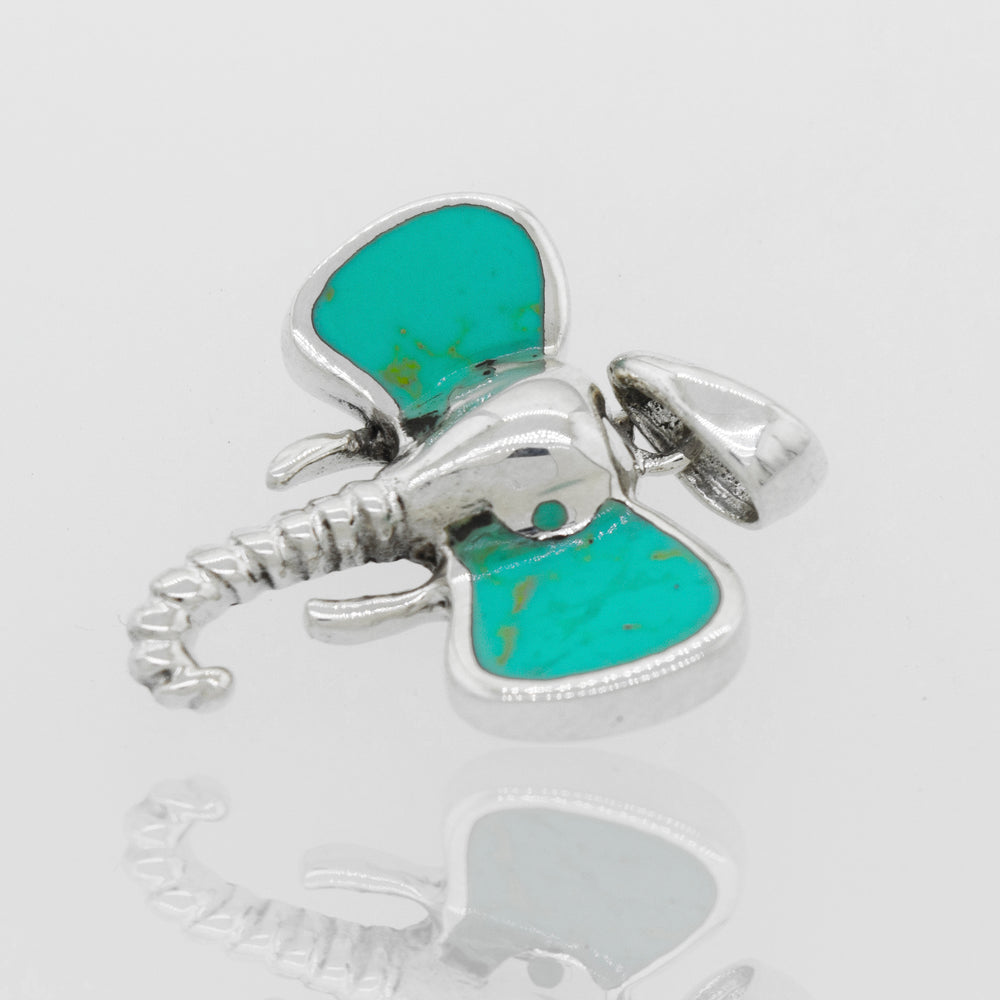 A Super Silver Elephant Head Pendant With Stone with inlaid stone ears and a turquoise stone.
