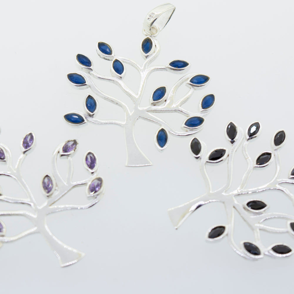 Three Super Silver Tree of Life pendants with blue and purple stones featuring faceted stone leaves.