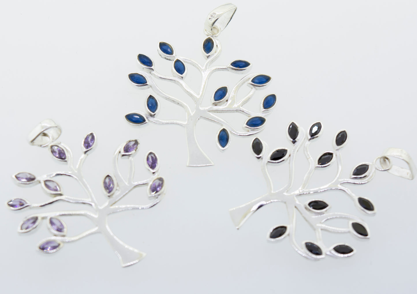 Three Super Silver Tree of Life pendants with blue and purple stones featuring faceted stone leaves.