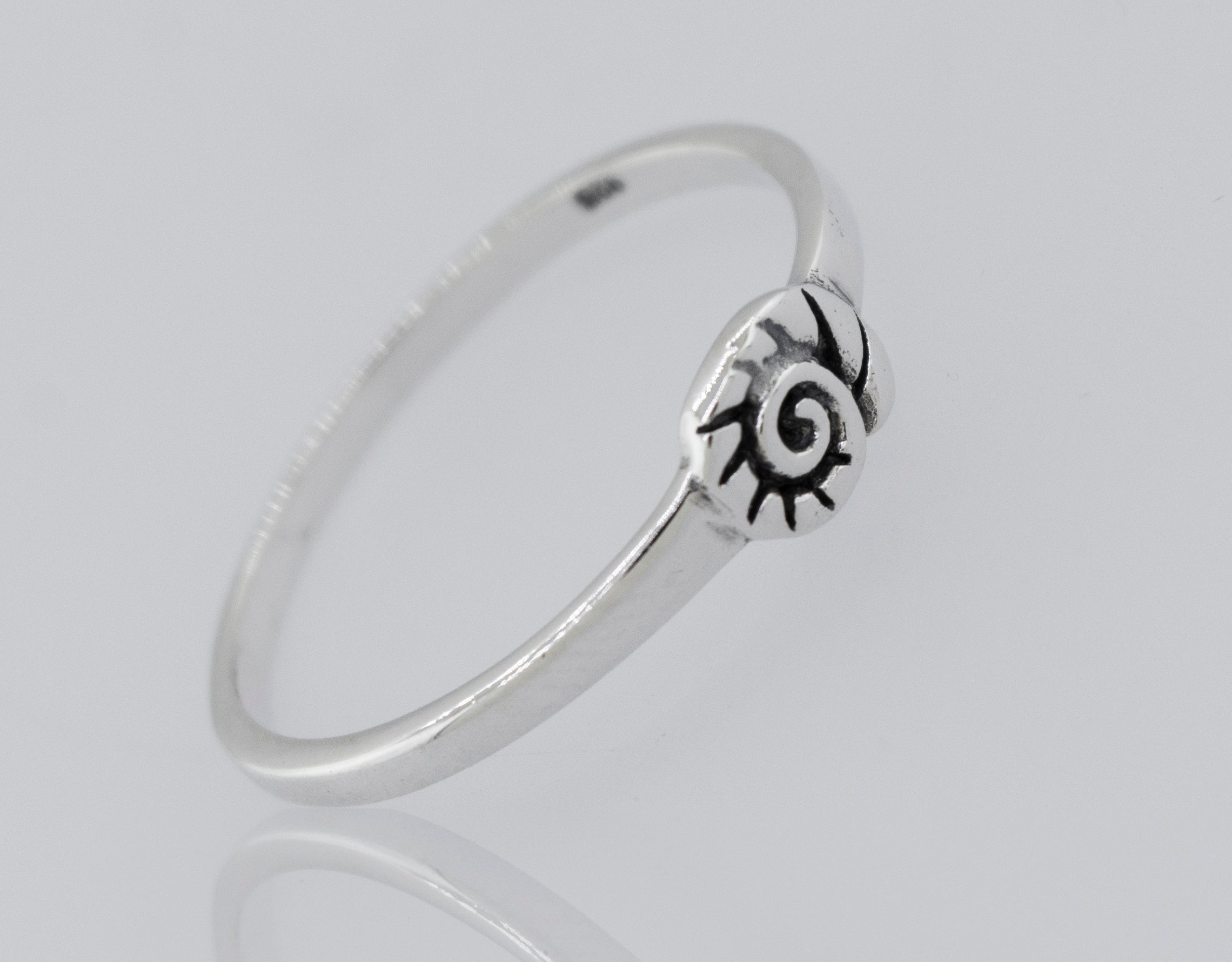 The Silver Nautilus Ring is a slim, high-polish 925 sterling silver band with a small engraved spiral sun design at the front, shown on a white background.