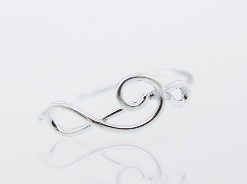 A Super Silver Horizontal Treble Clef Ring with a treble clef design on a high polish white surface.