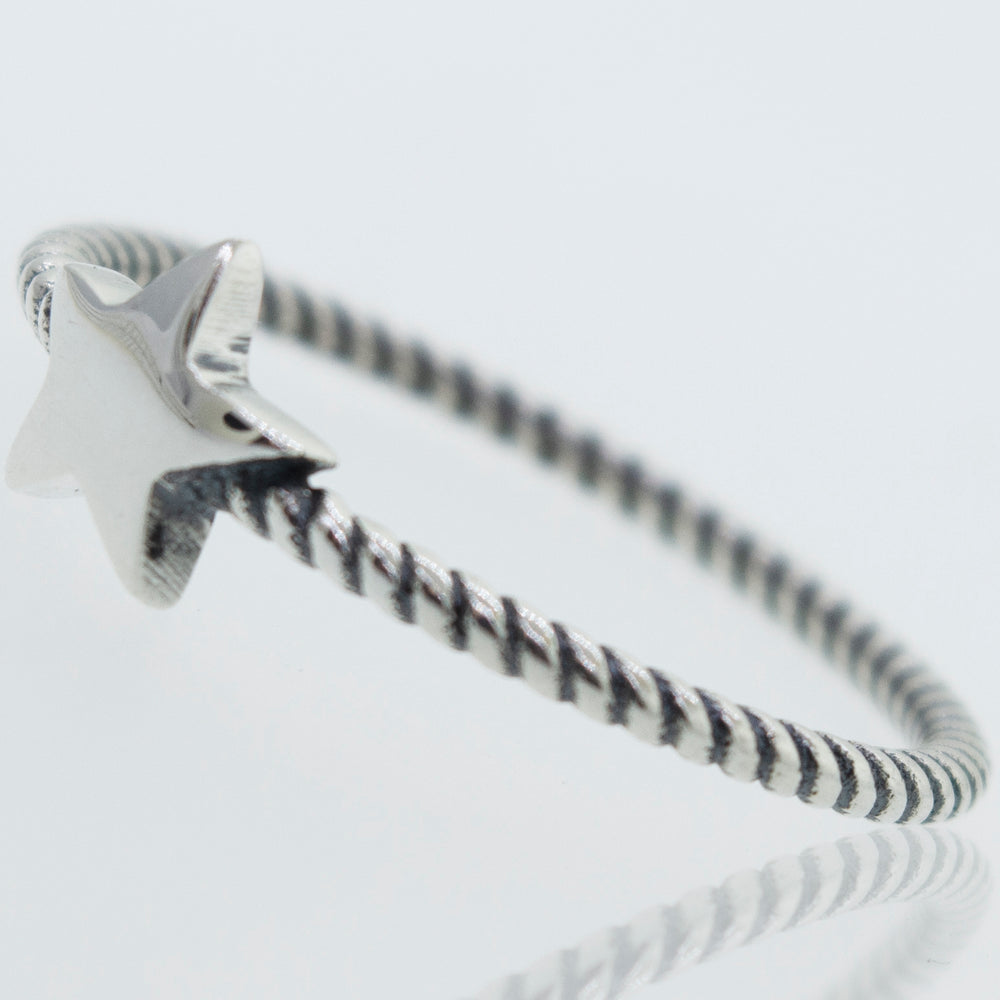 An oxidized Super Silver star ring with a rope design band on a white surface.