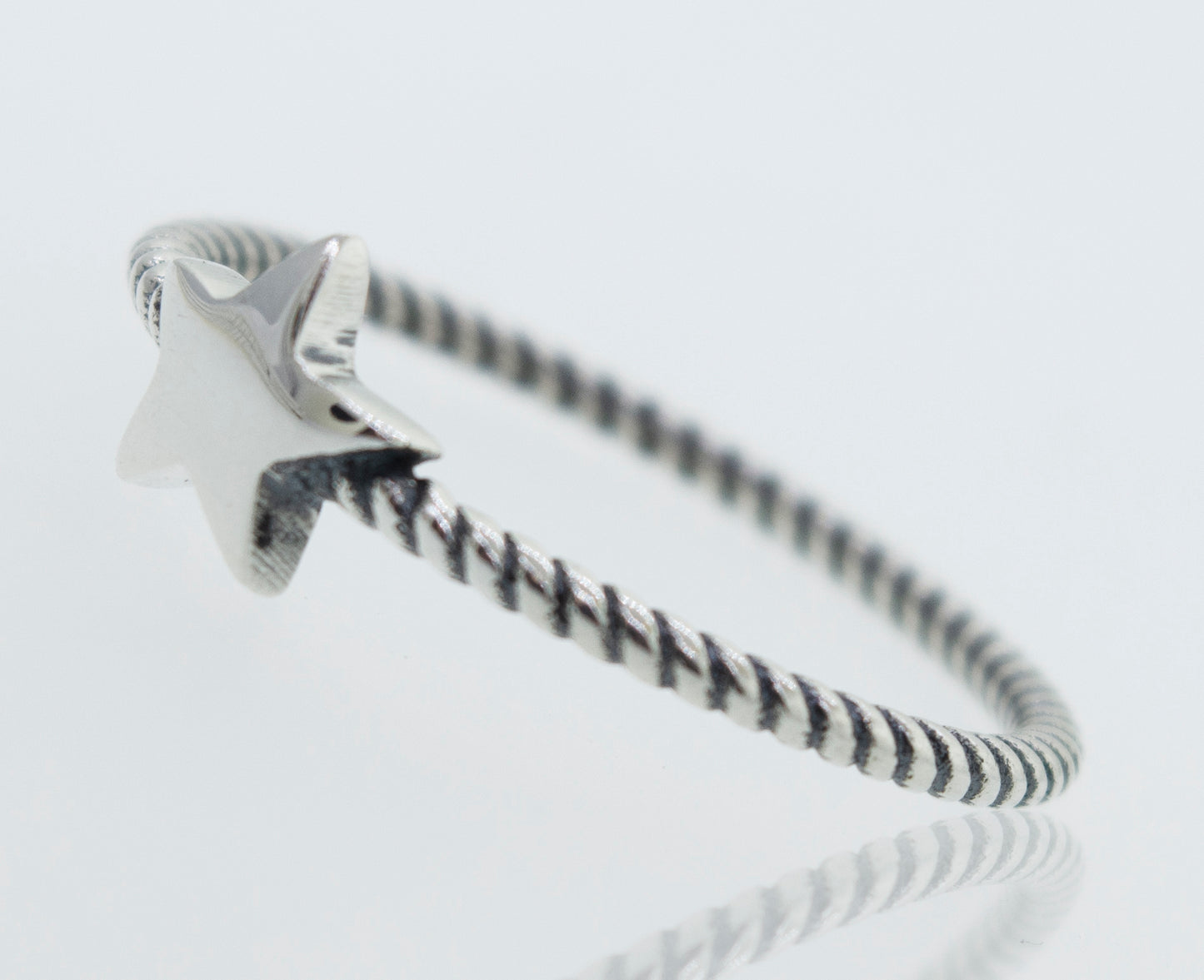 An oxidized Super Silver star ring with a rope design band on a white surface.
