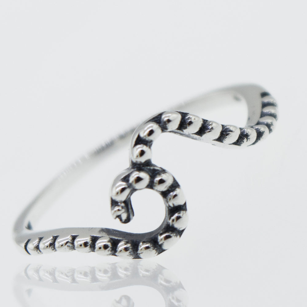 A stackable, octopus shaped Dotted Wave Ring on a white surface.