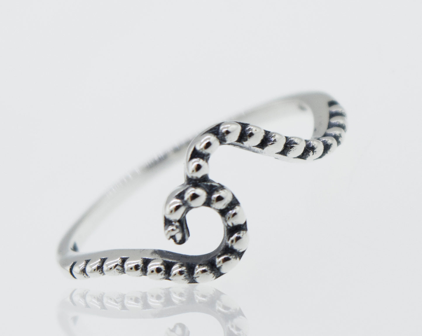 A stackable, octopus shaped Dotted Wave Ring on a white surface.