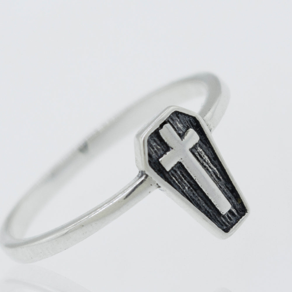A silver Coffin Ring with a cross on it.
