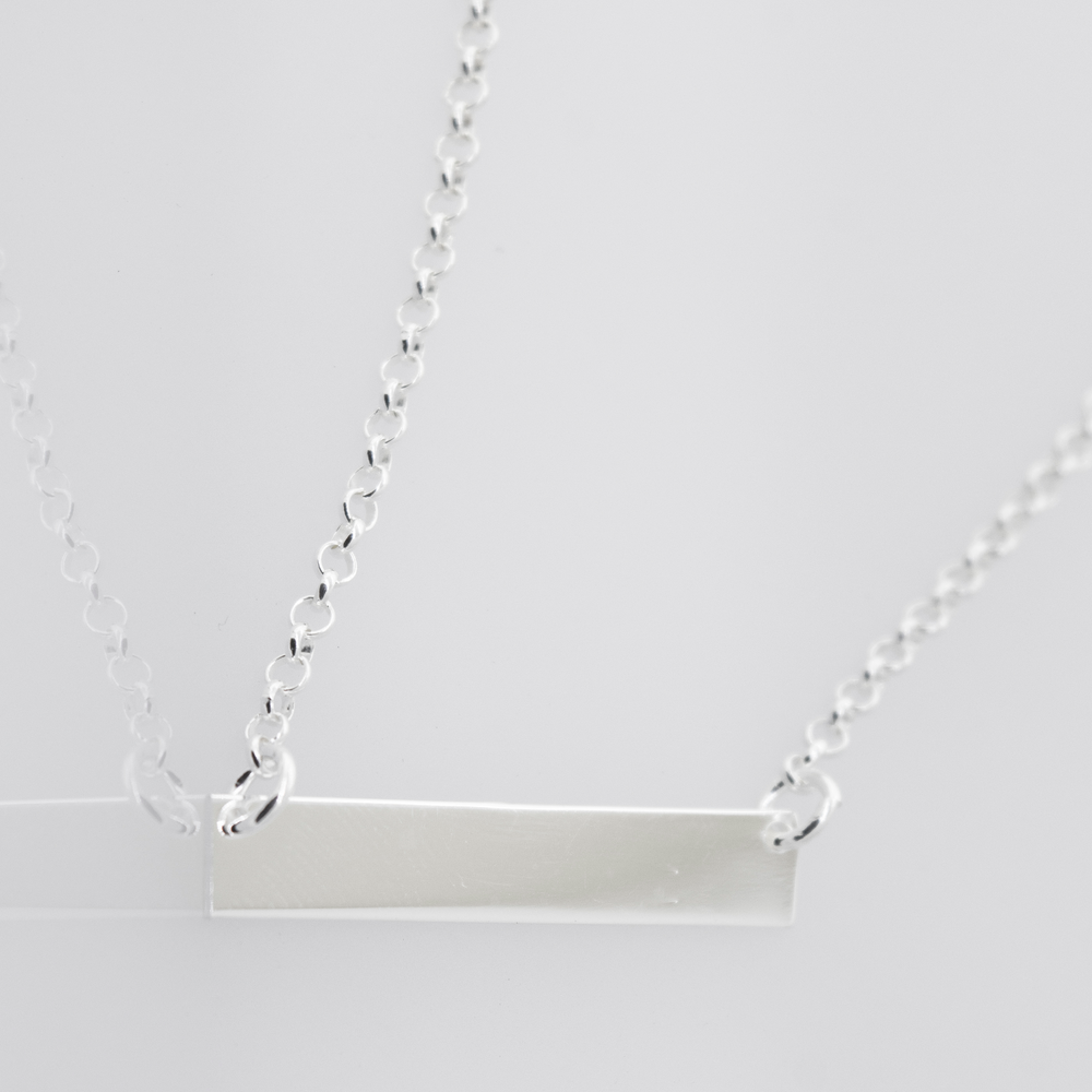 Two Dainty Nameplate Necklaces by Super Silver with adjustable chains on a white background.
