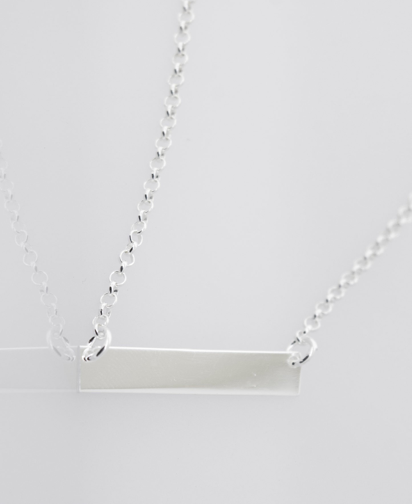 Two Dainty Nameplate Necklaces by Super Silver with adjustable chains on a white background.