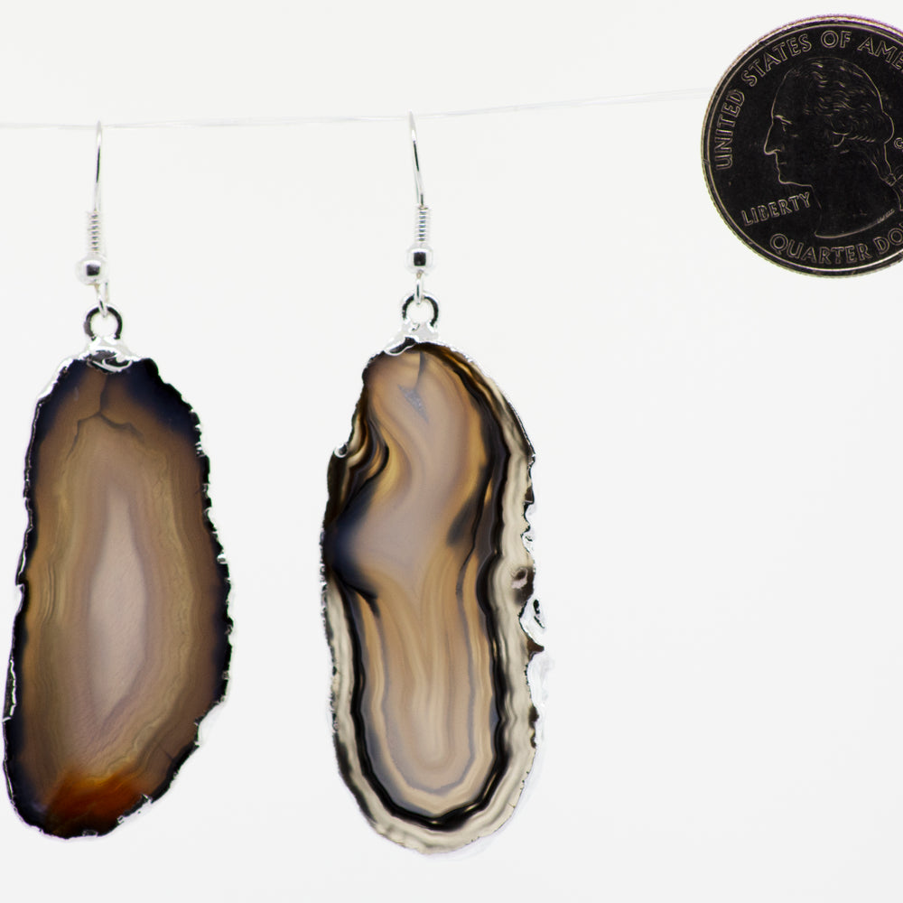 
                  
                    A pair of Dyed Agate Slice Earrings from Super Silver, with various colors, hanging from a string with a silver-plated border.
                  
                