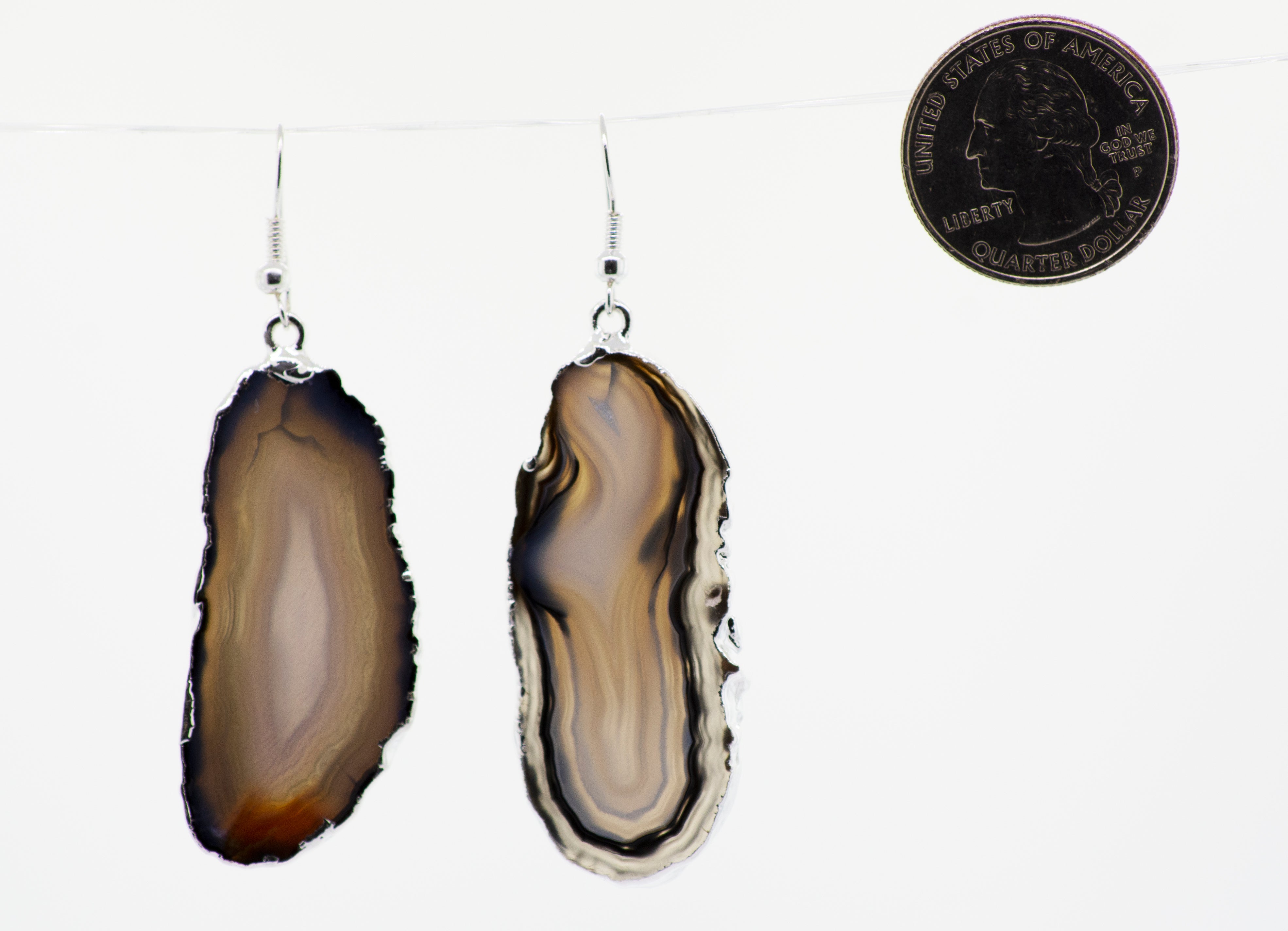 A pair of Dyed Agate Slice Earrings from Super Silver, with various colors, hanging from a string with a silver-plated border.
