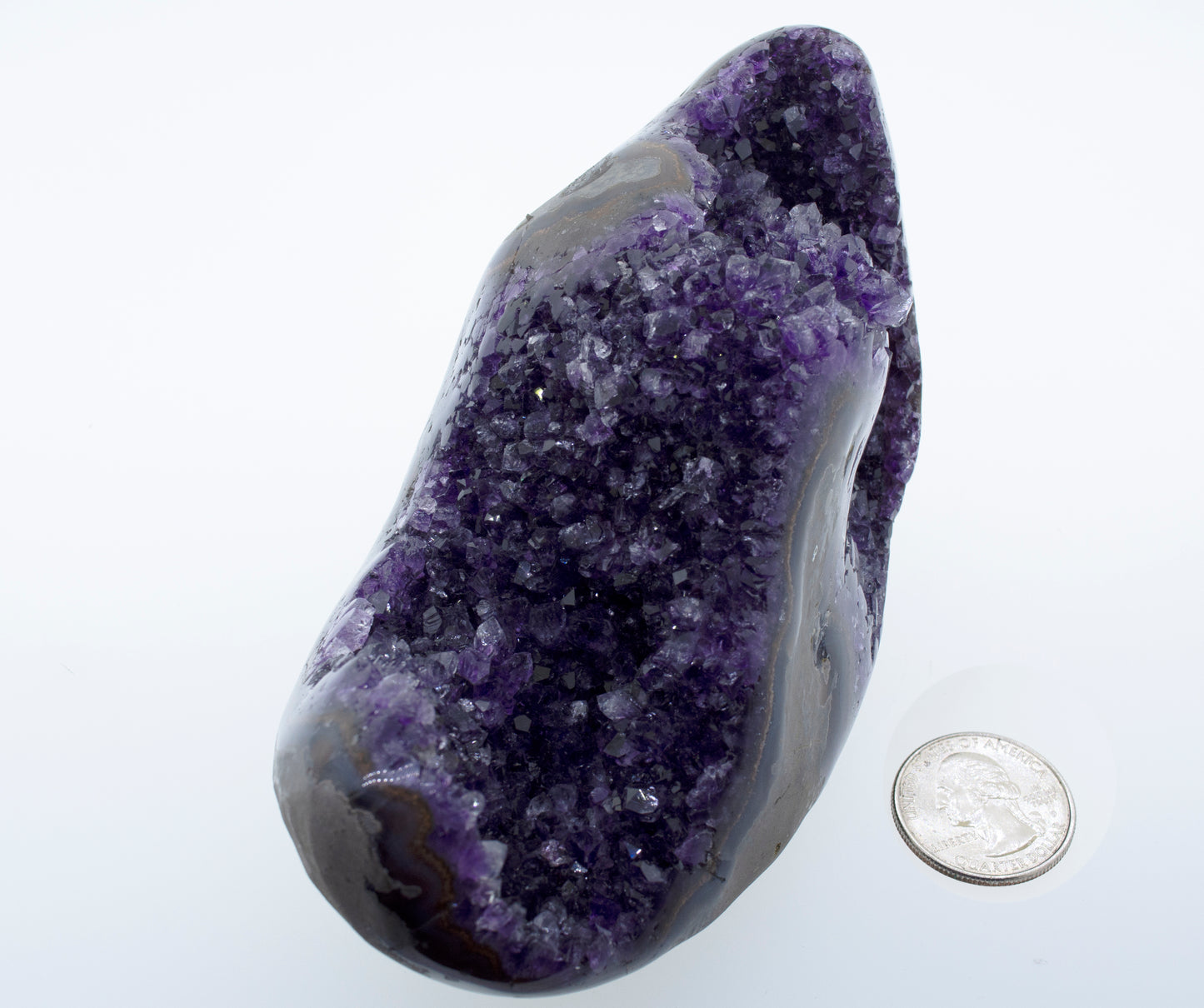 
                  
                    An Egg Shaped Amethyst Geode with a purple amethyst rock next to a dime.
                  
                