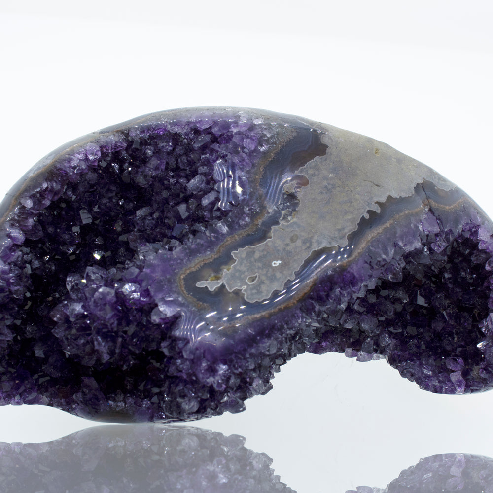 
                  
                    An Egg Shaped Amethyst Geode on a white surface.
                  
                
