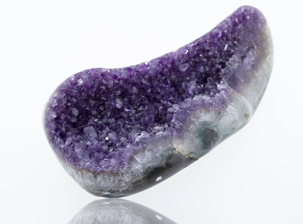 An Oval Shaped Amethyst Geode on a white surface.