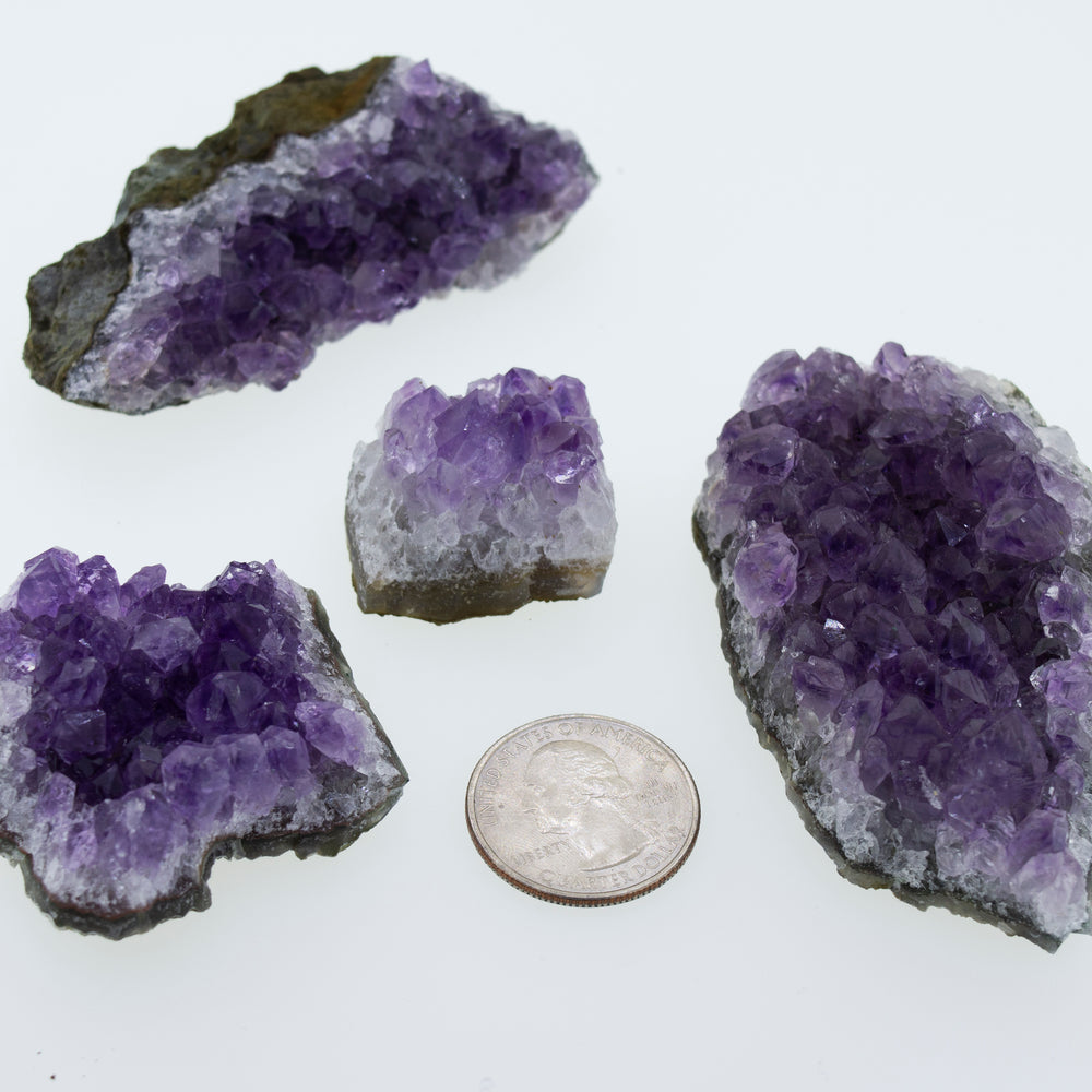 
                  
                    Four purple Amethyst Geodes in Varying Sizes next to a dime, perfect for boho decor or geode enthusiasts.
                  
                