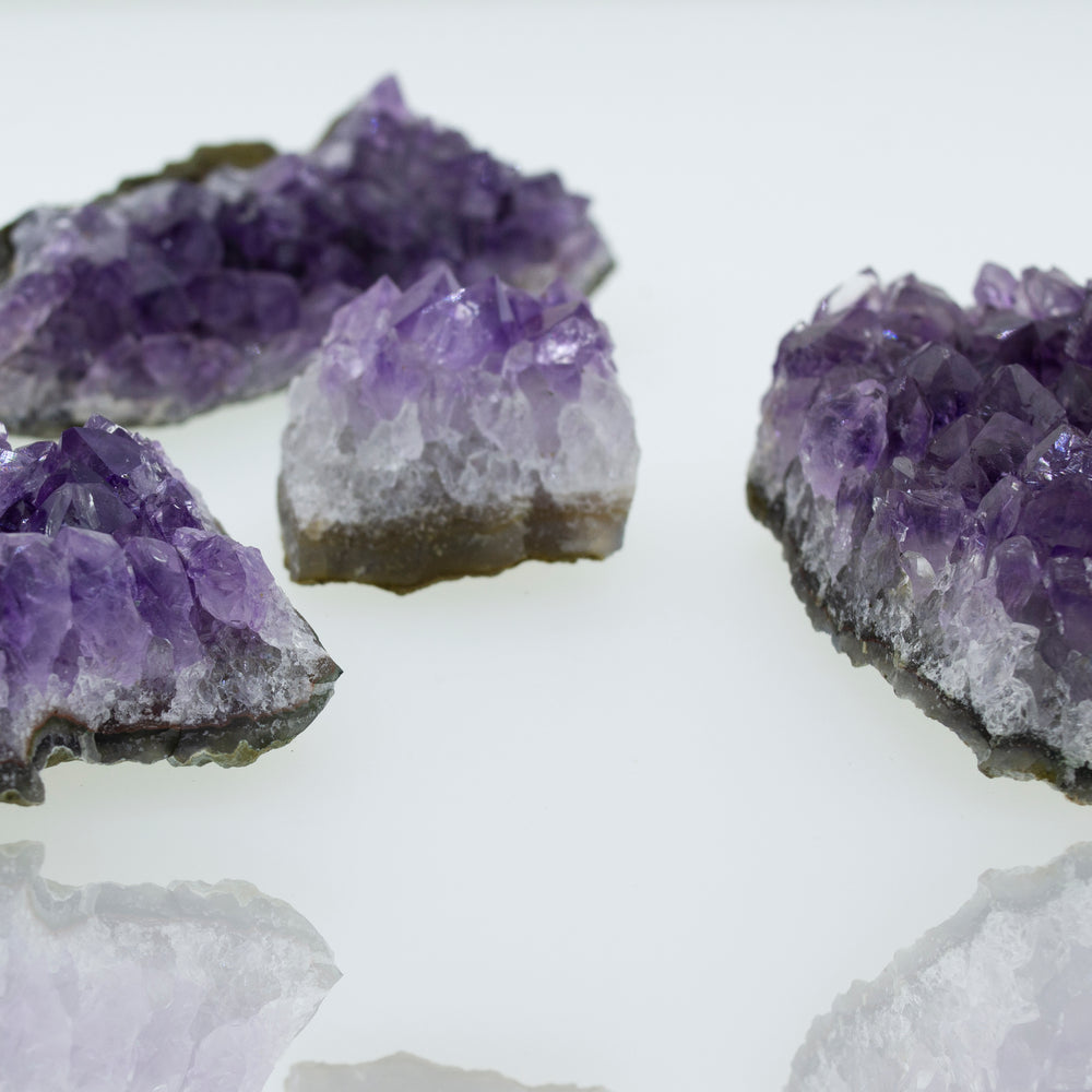 
                  
                    Three pieces of Amethyst Geodes in Varying Sizes, perfect for boho decor, placed on a white surface.
                  
                