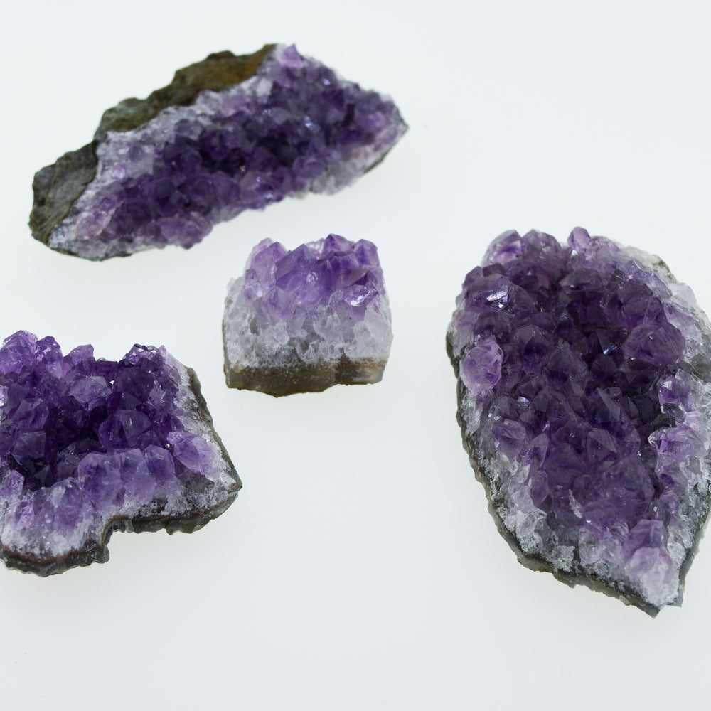 
                  
                    Three pieces of Amethyst Geodes in Varying Sizes on a white surface.
                  
                