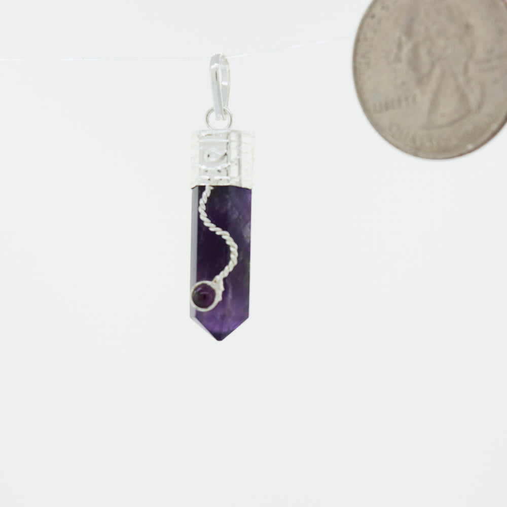 
                  
                    An Amethyst Pendant with Decorated Bail and Small Garnet Stone hanging from a Super Silver chain.
                  
                