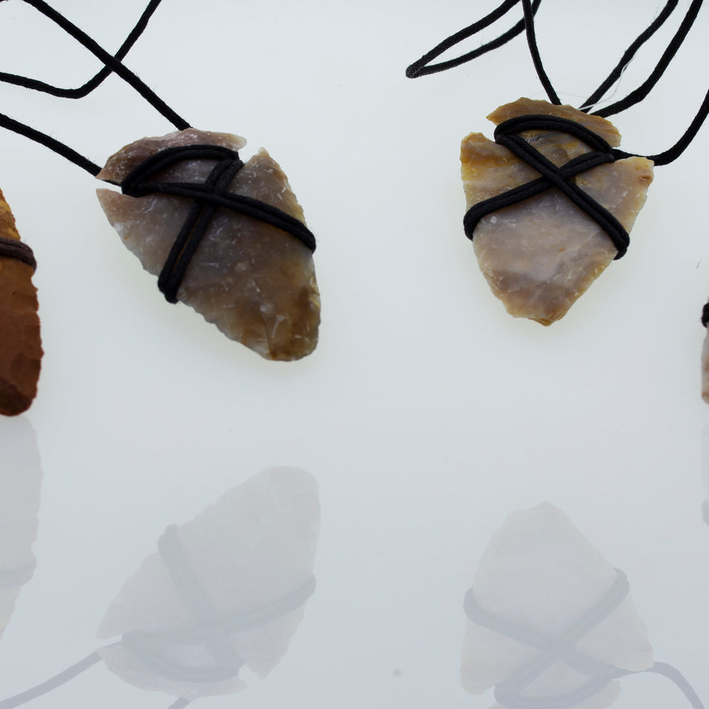 A group of Super Silver Arrowhead Necklaces with Cord on a white surface.