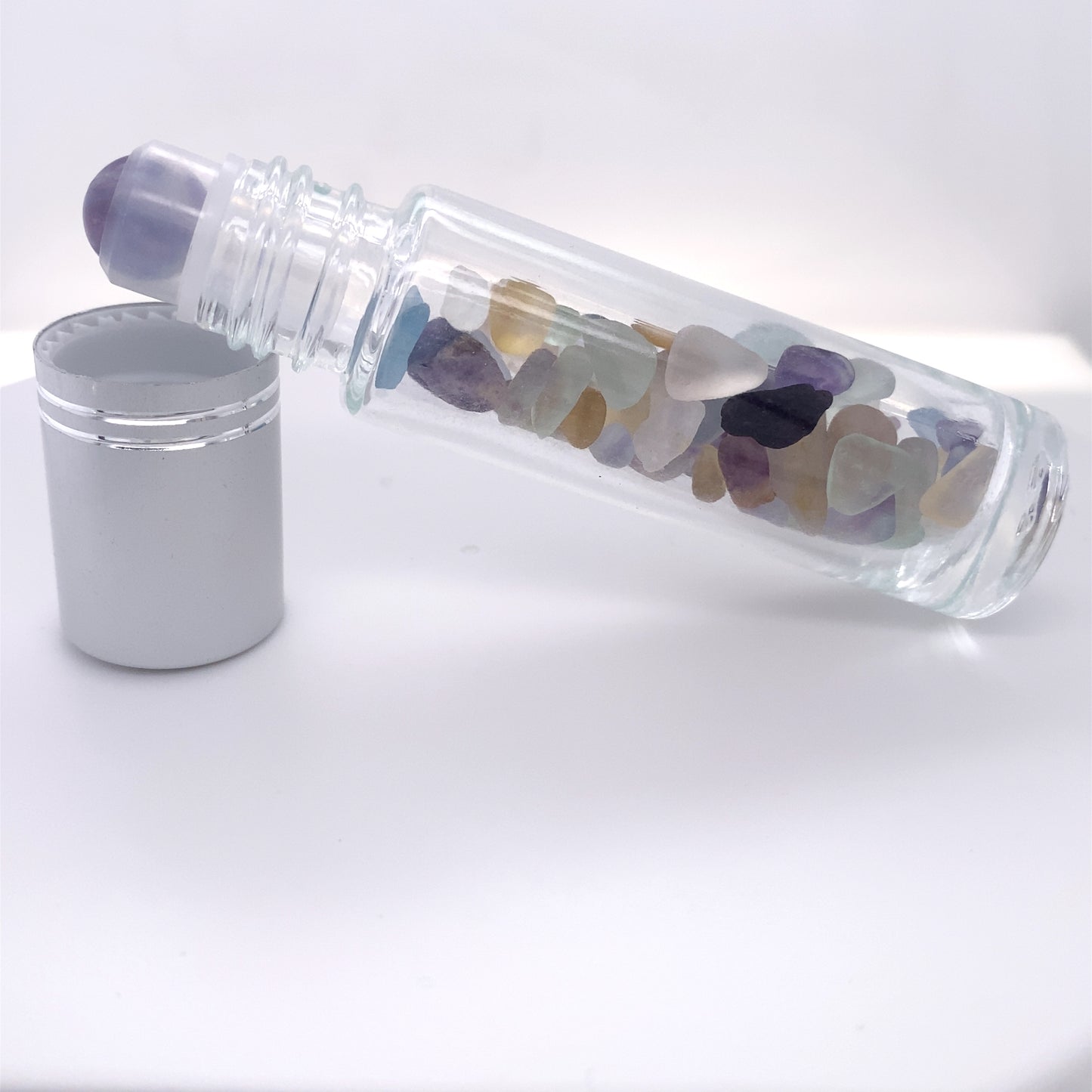 A beautiful glass bottle with stones, perfect for self-care and stone rolling, the Stone Essential Oil Roller.